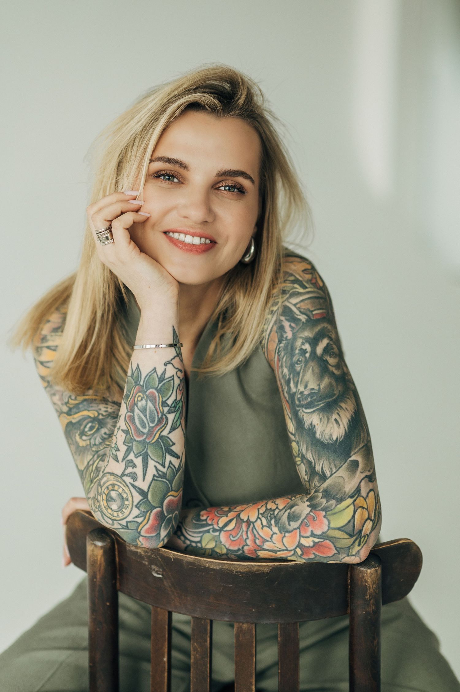 Fashion portrait featuring floral printed sleeve details and olive green top against a light background.