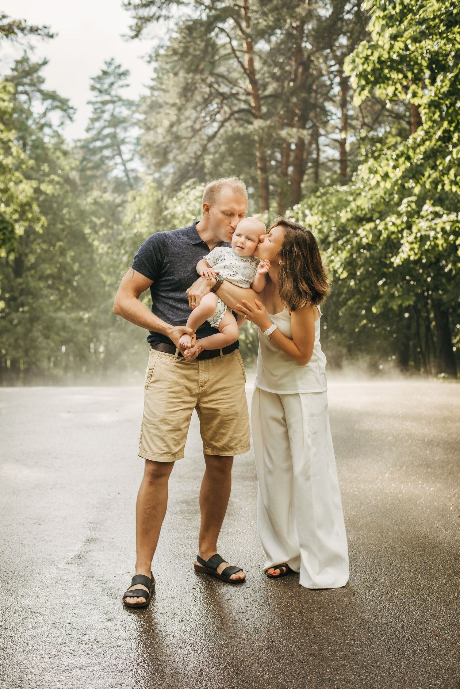 Family sharing intimate moments together on a misty path surrounded by pine trees.