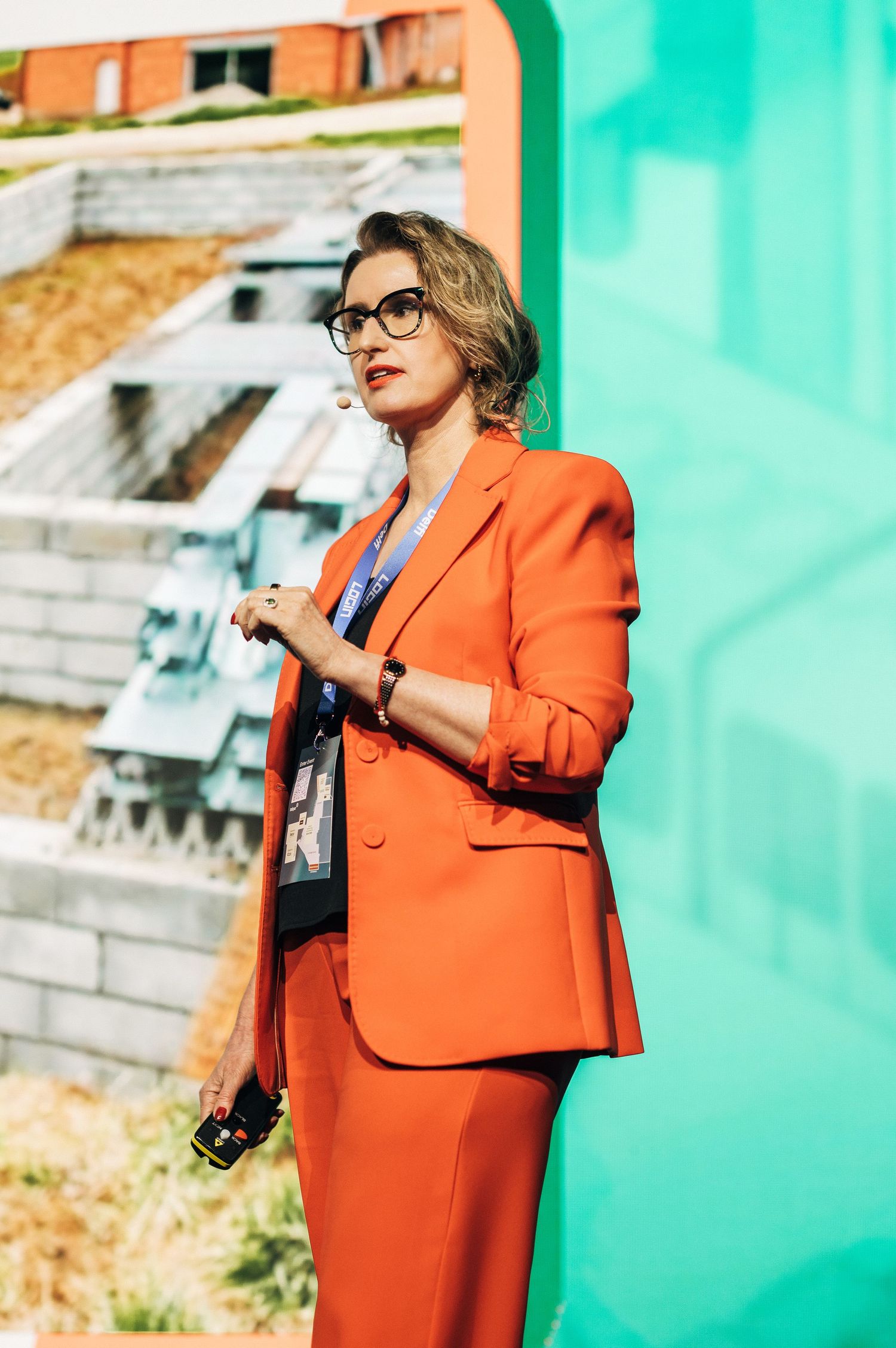 A person in a vibrant orange blazer poses against a turquoise wall in multiple candid shots.