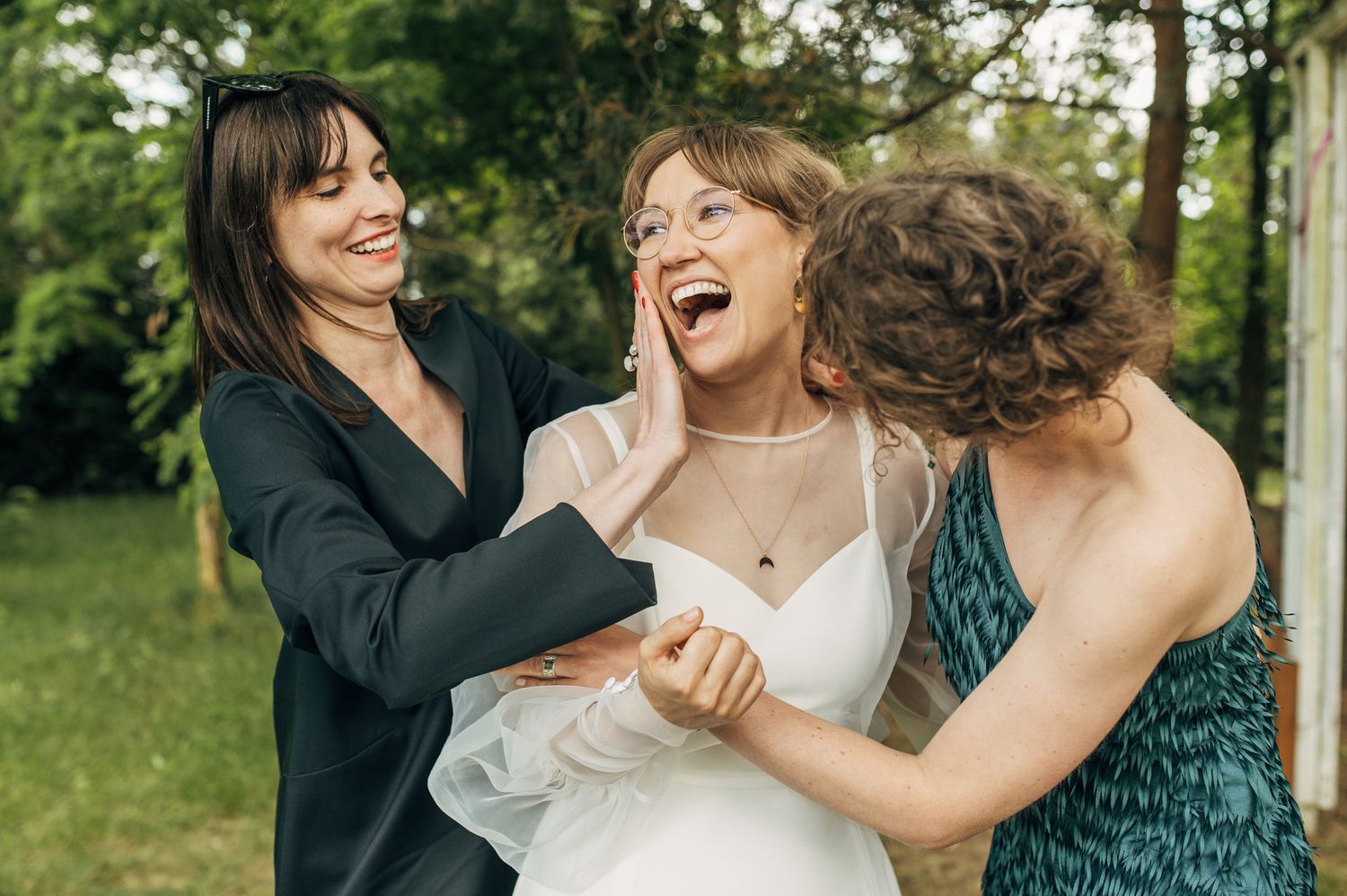 Joyful group photo of wedding party members sharing laughs in a garden.