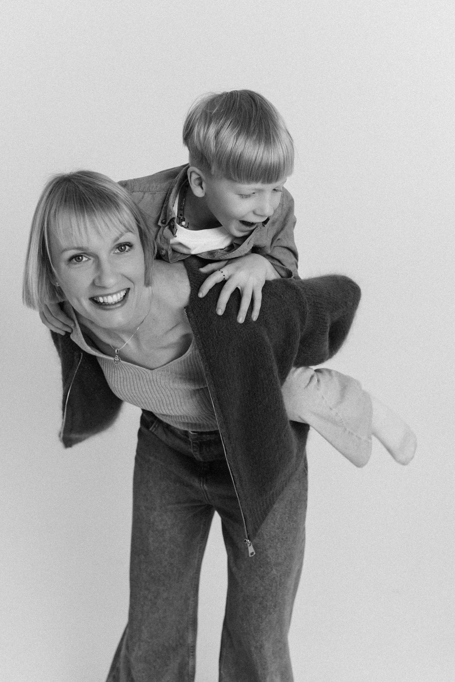 A series of black and white photos showing someone bending down in jeans and sweater in different poses against a white backdrop.