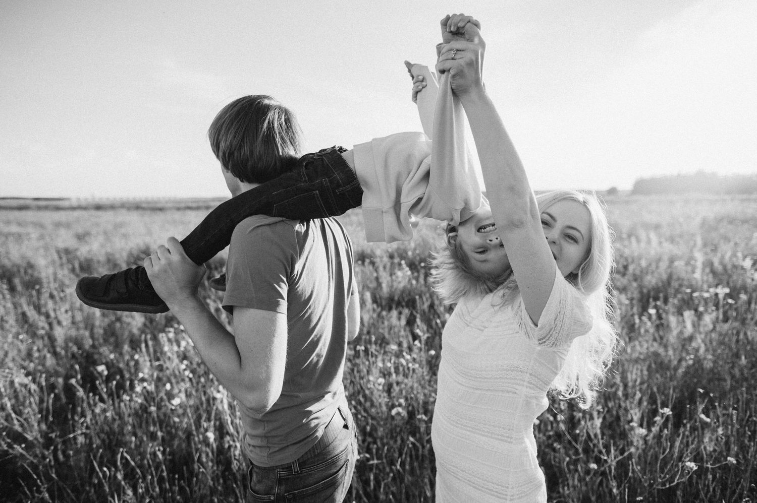 Two people sharing playful moments together in a sunlit field.