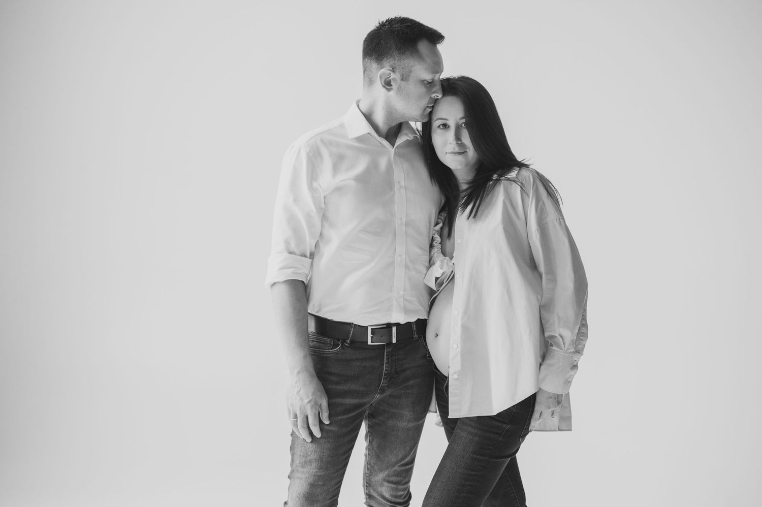 Black and white portrait series of couple sharing intimate moments against white background.