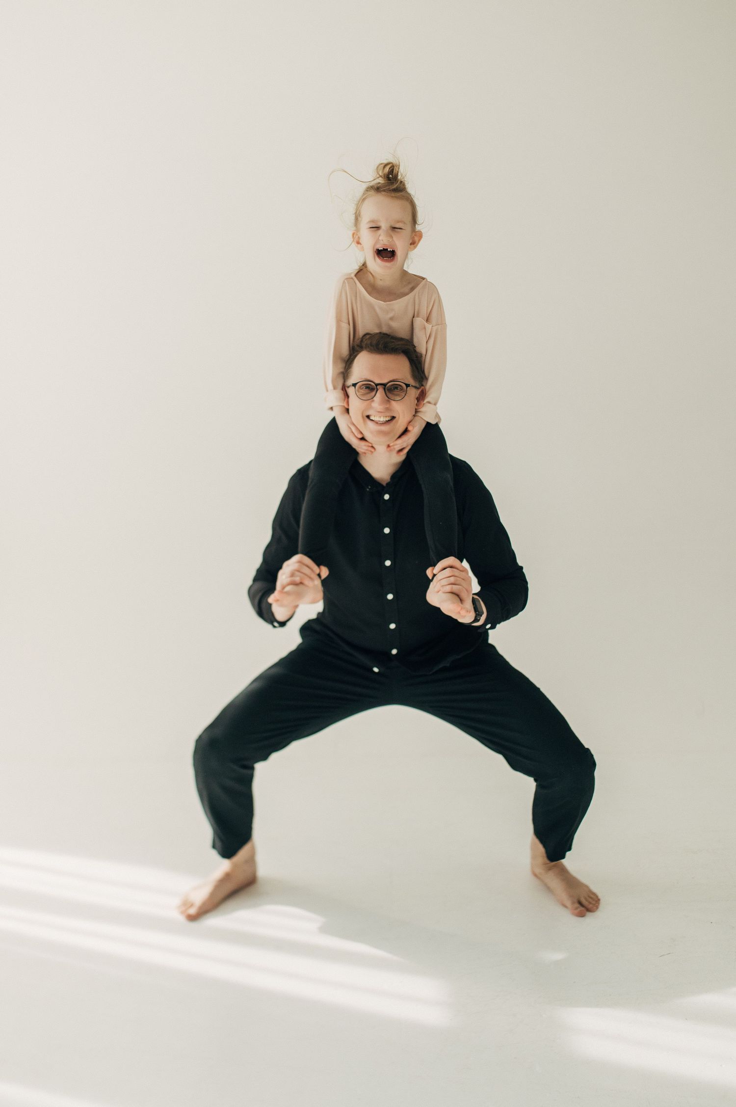 A playful series of jumps captured against a white wall showing movement and joy in black clothing.