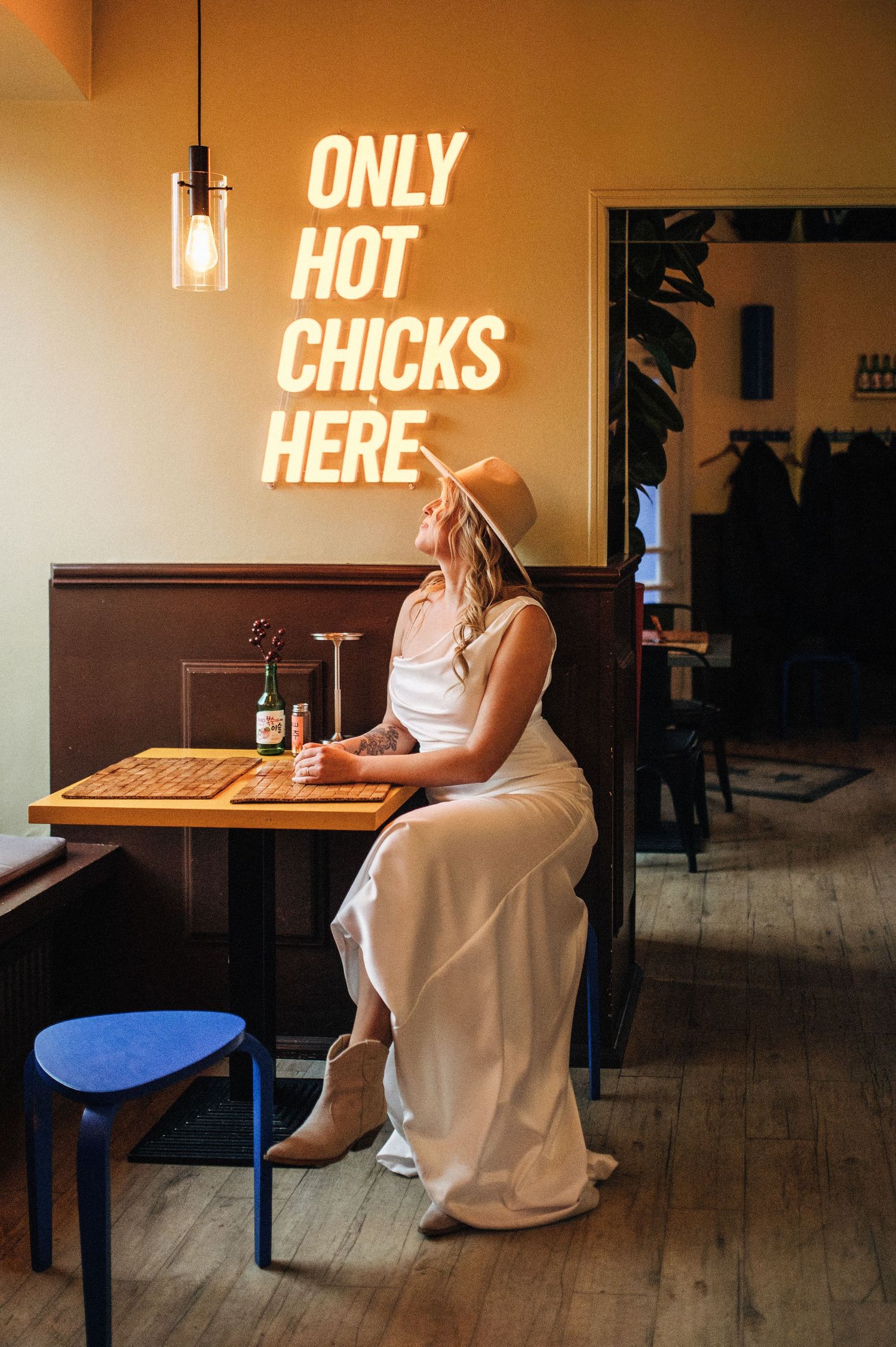 Three connected images show someone in white dress sitting alone at a cafe table with neon signs visible in background.
