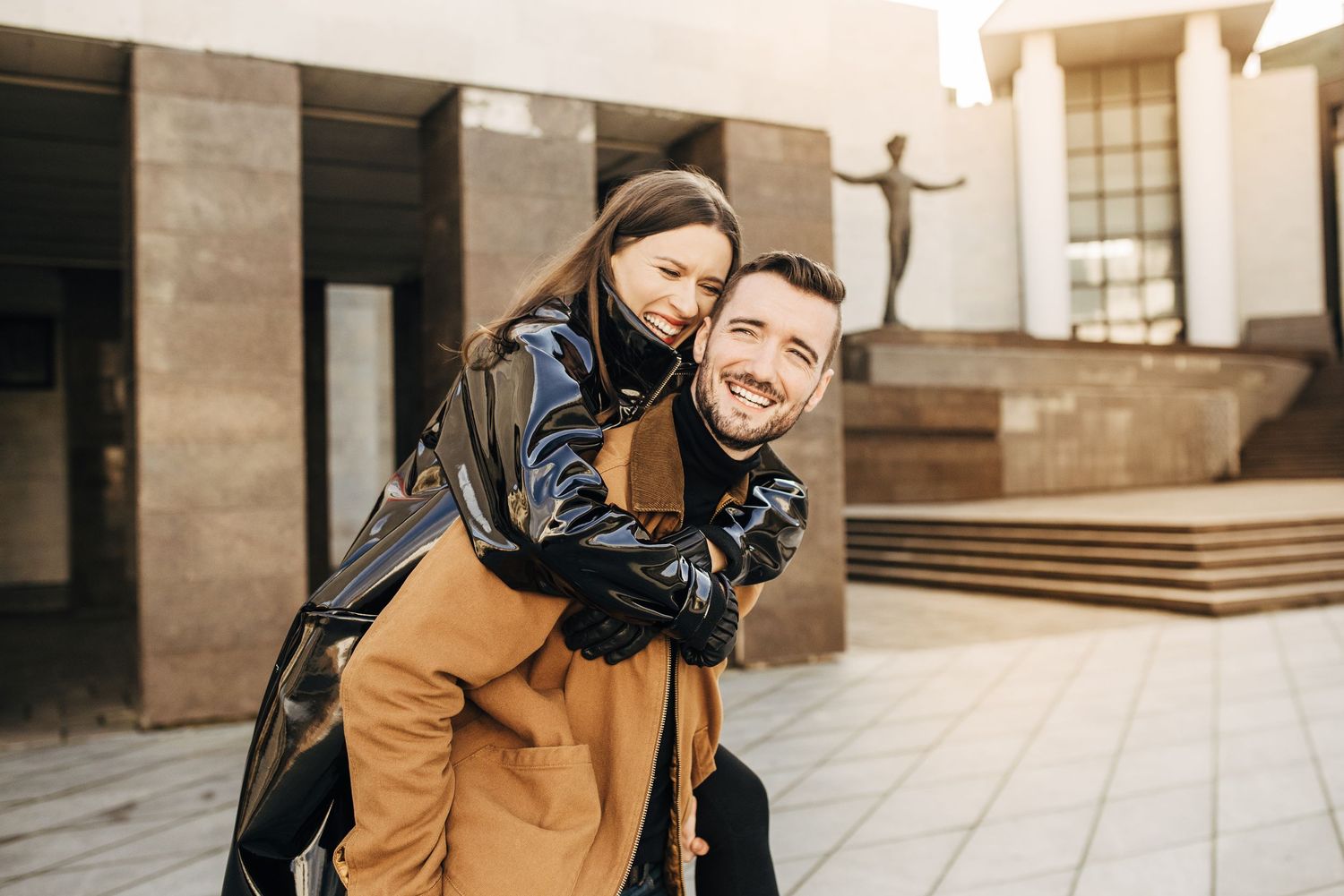 Candid moments captured between couple in urban setting with stone architecture.