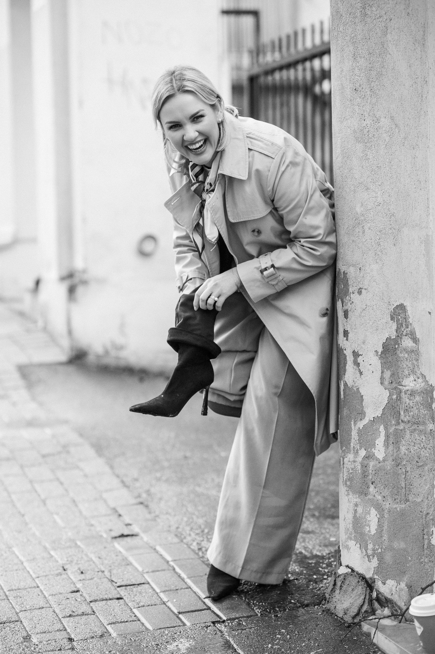 Black and white portrait series showing playful moments near an urban wall.