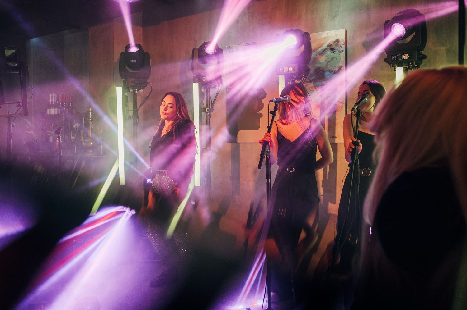 Concert venue with vibrant purple stage lighting and laser beams creating dynamic visual effects.