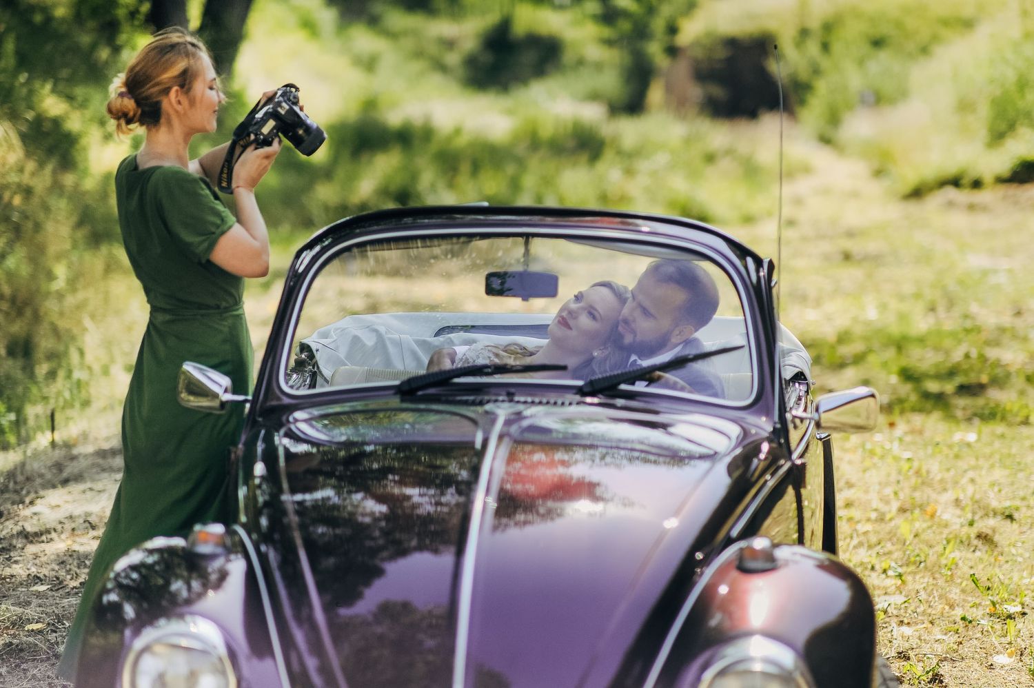 Classic purple vintage car parked on green grass during an outdoor photoshoot.