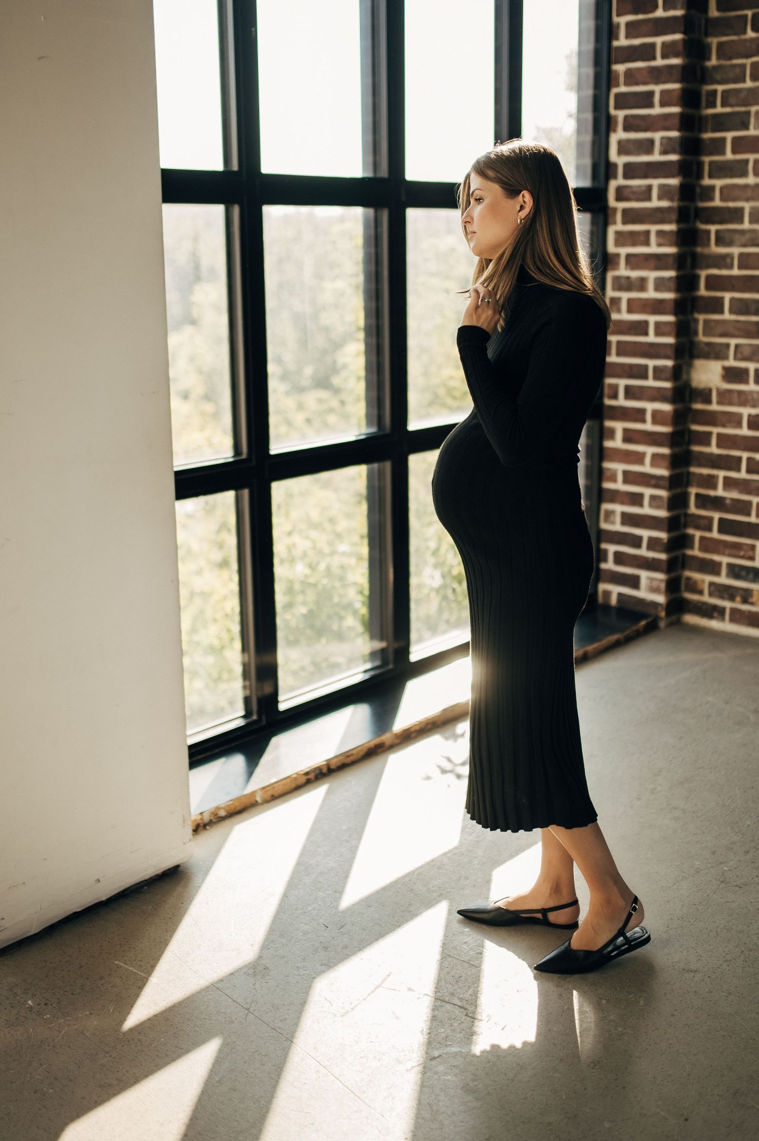 Artistic window light portraits in industrial brick building creating dramatic shadows.