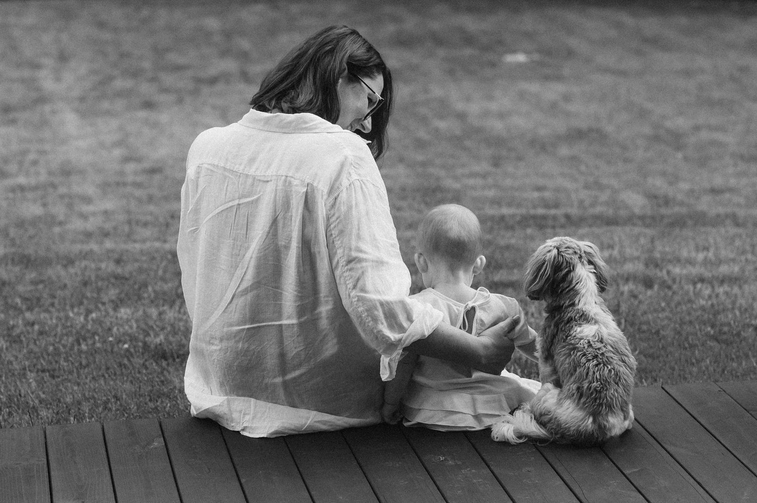 Family and pets relaxing together outdoors on wooden deck.