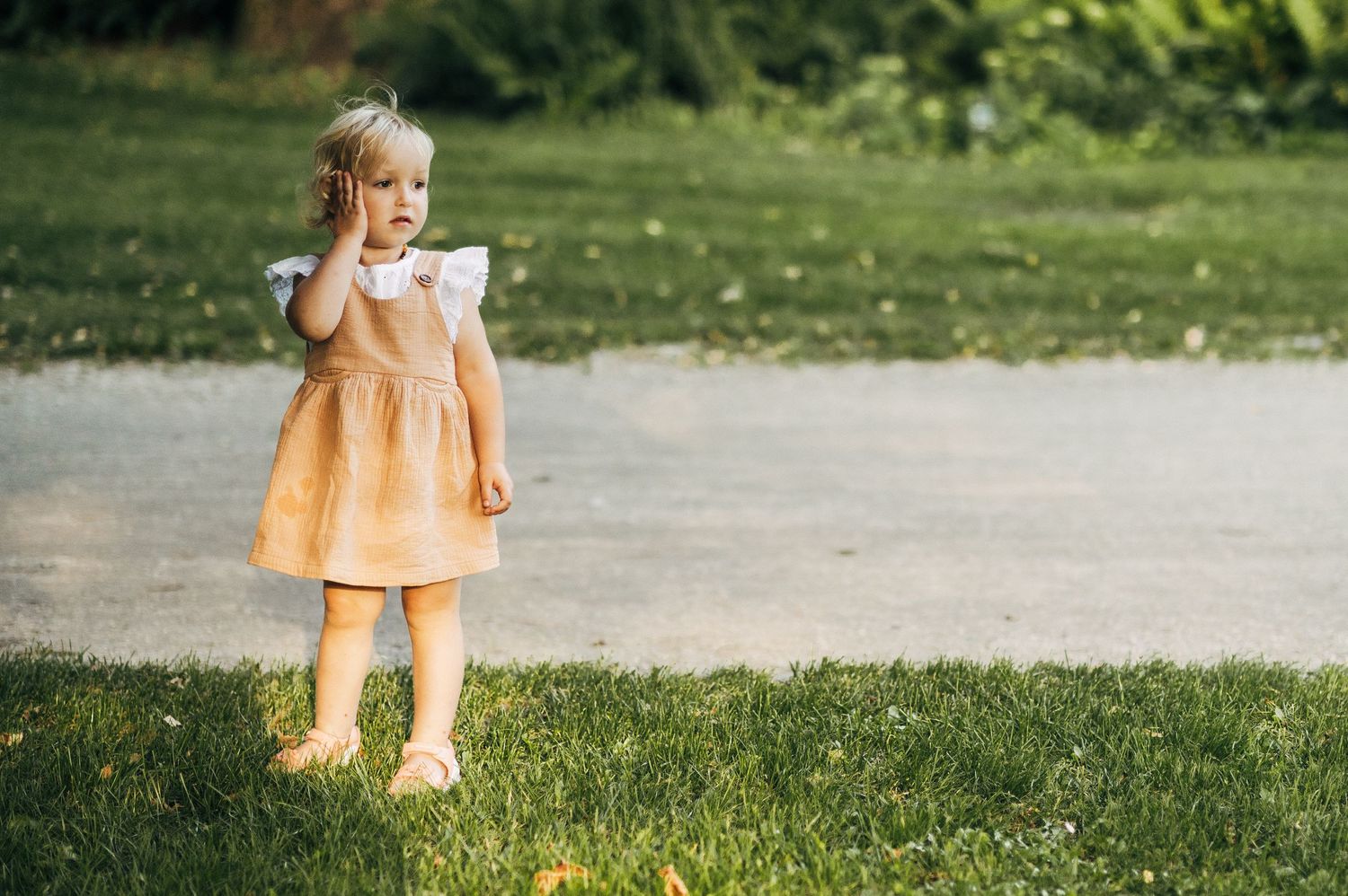 Children playing in bright summer dresses on green grass.