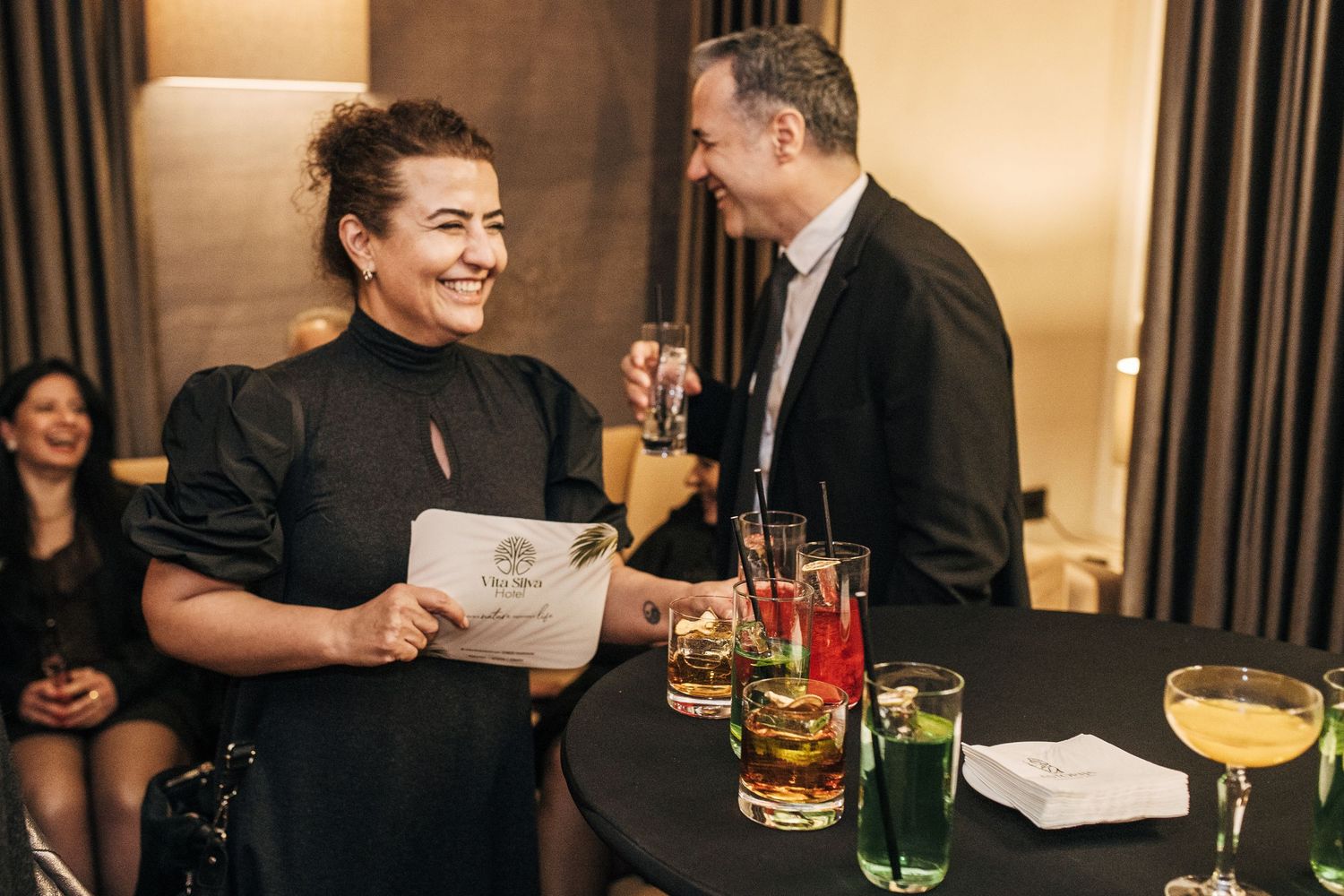 Restaurant staff and guests interact at an upscale event with cocktails and drinks on display.