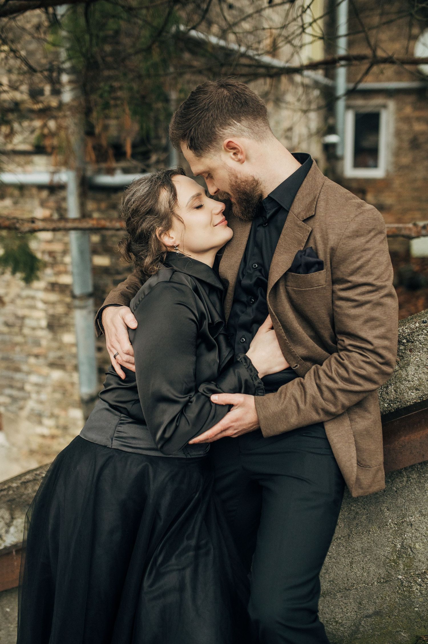 Couple embracing near stone wall architecture during romantic photoshoot.
