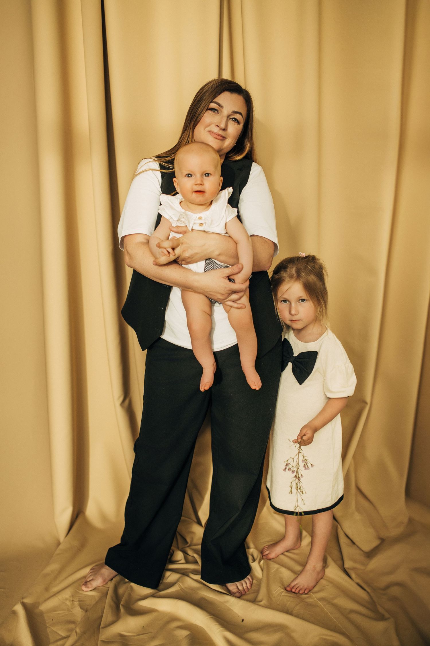 Family portraits against golden curtain backdrop showing tender moments together.