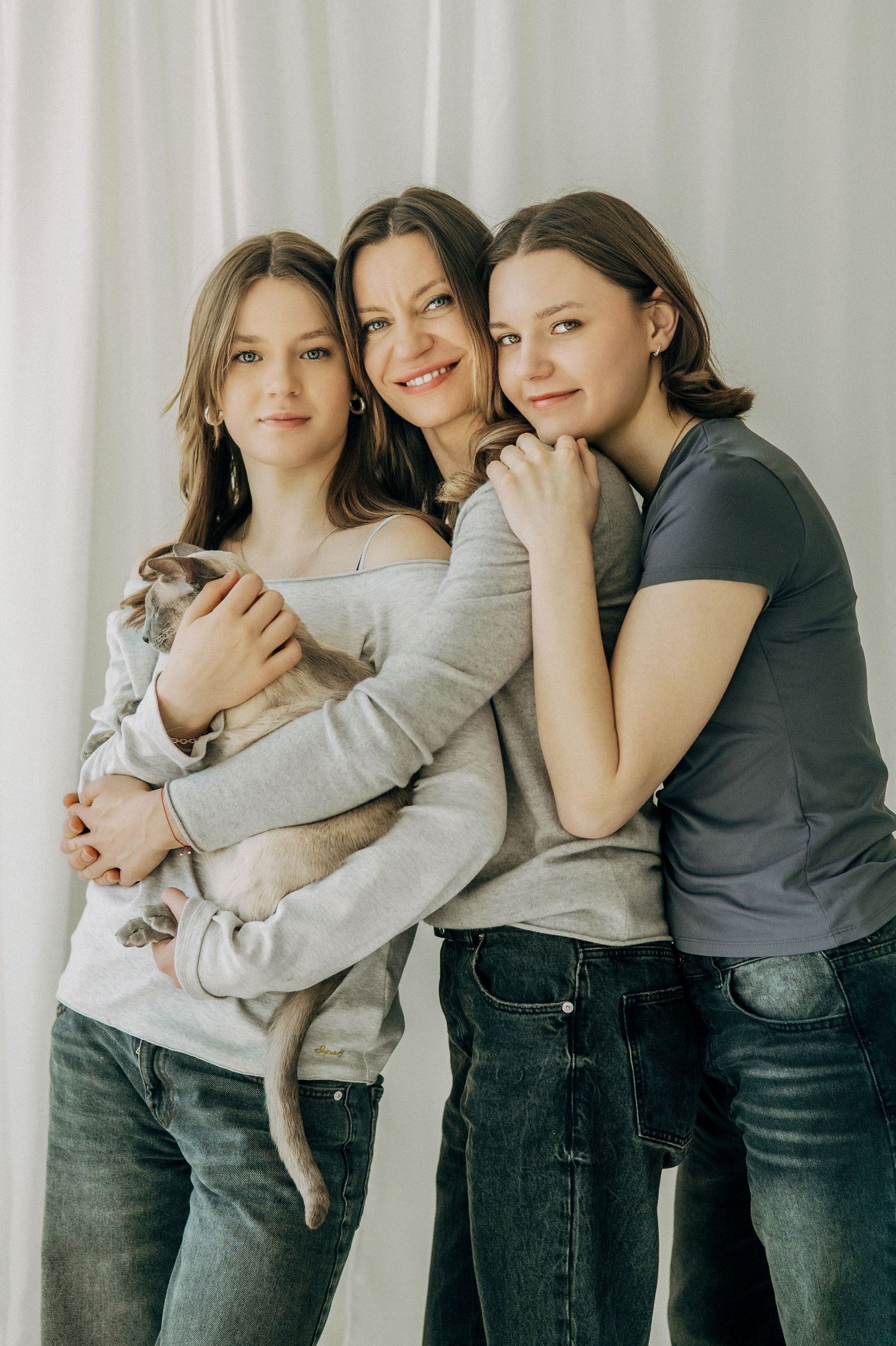 Group of friends in casual attire share warm embraces against a white backdrop.