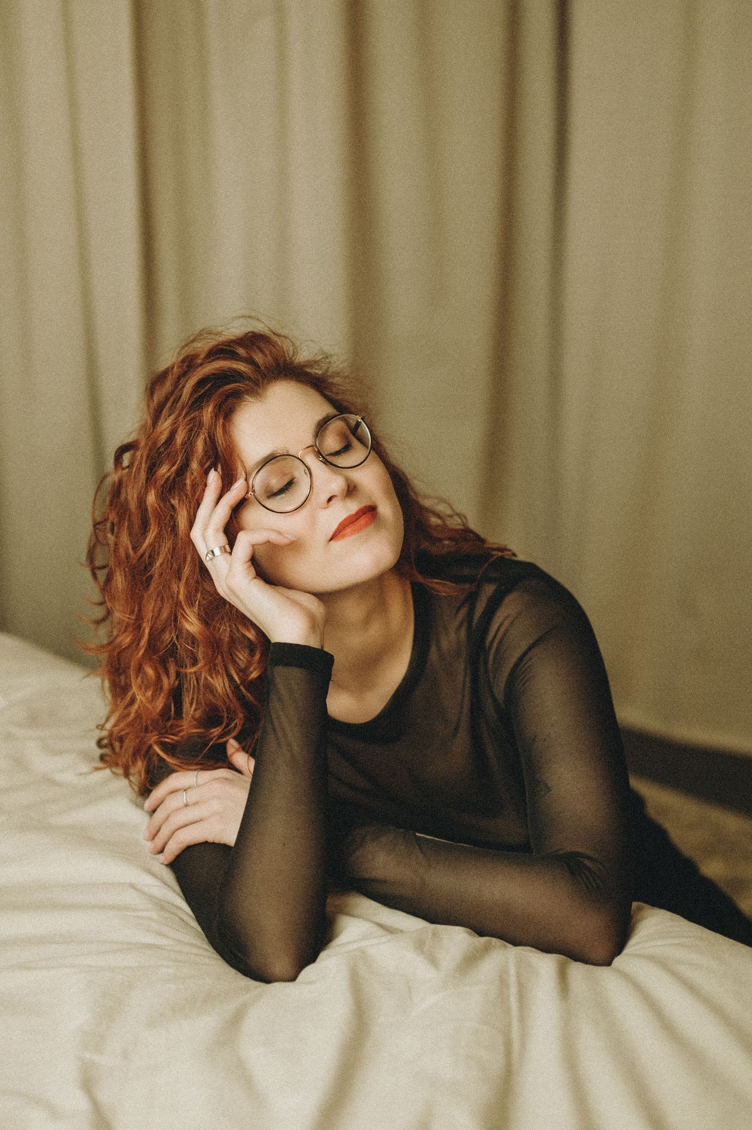 Portrait series showing person in sheer black top relaxing on bed with warm lighting.