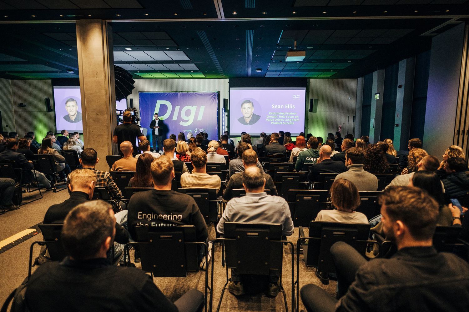 A crowded tech conference room filled with attendees watching a presentation on digital technology and innovation.