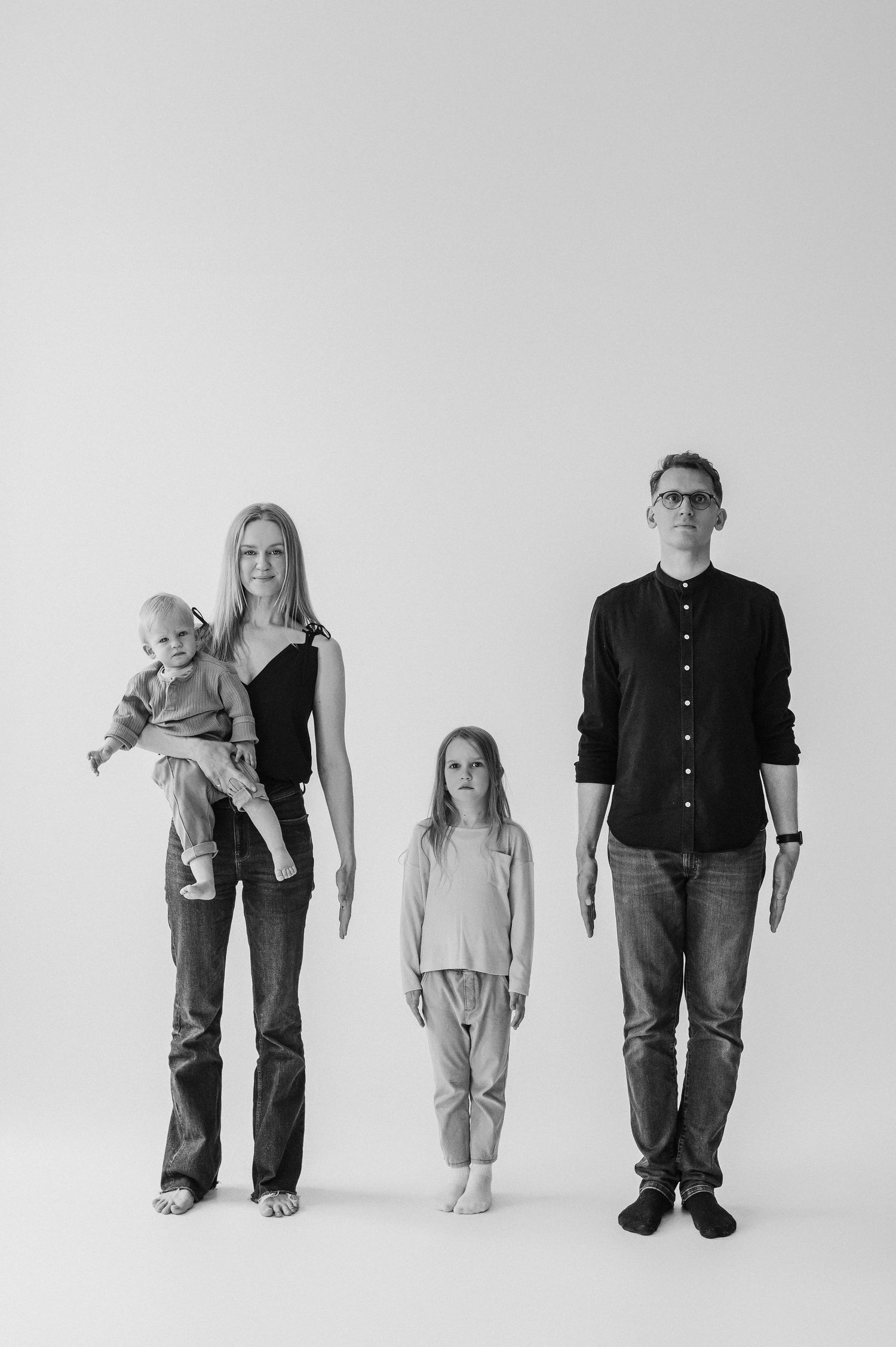 A minimalist black and white photo sequence showing a family group in various poses against a plain background.