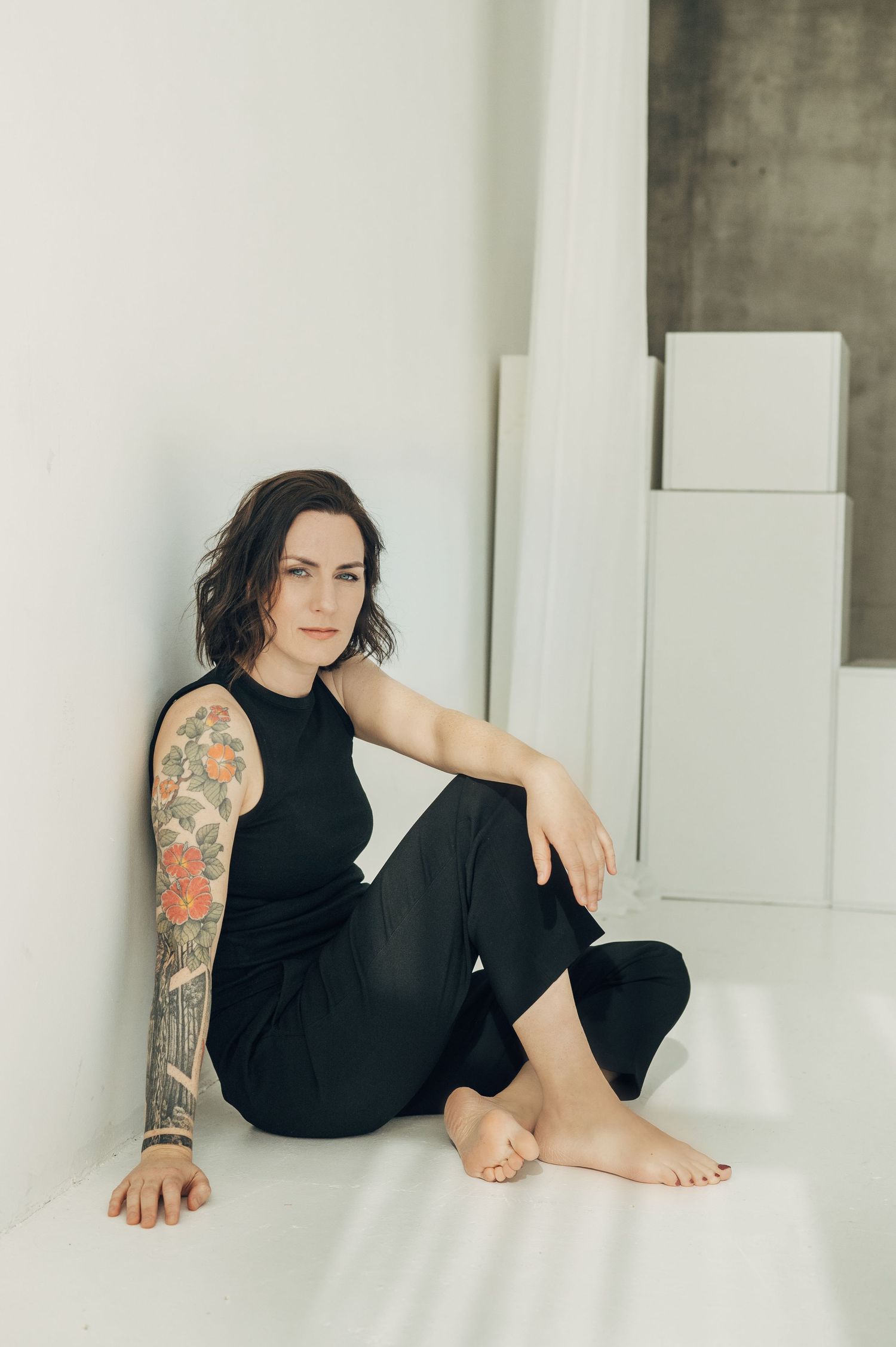 Minimalist portrait series showing tattoo art in black outfit against white background.