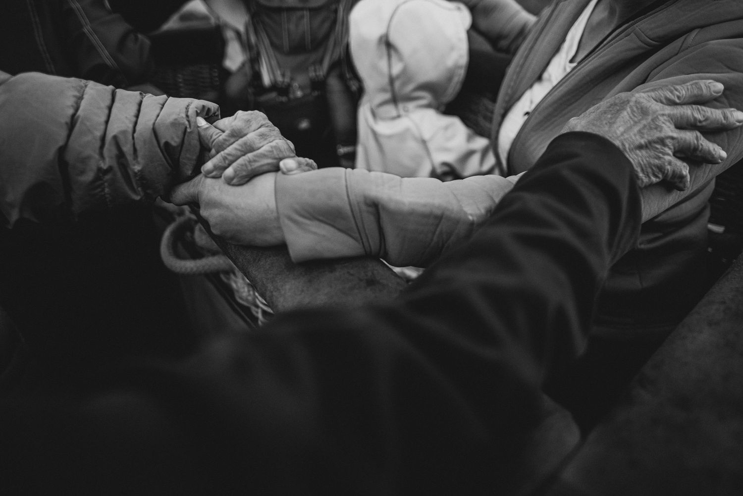 Black and white close-up of hands joined together in a meaningful gesture at a gathering.