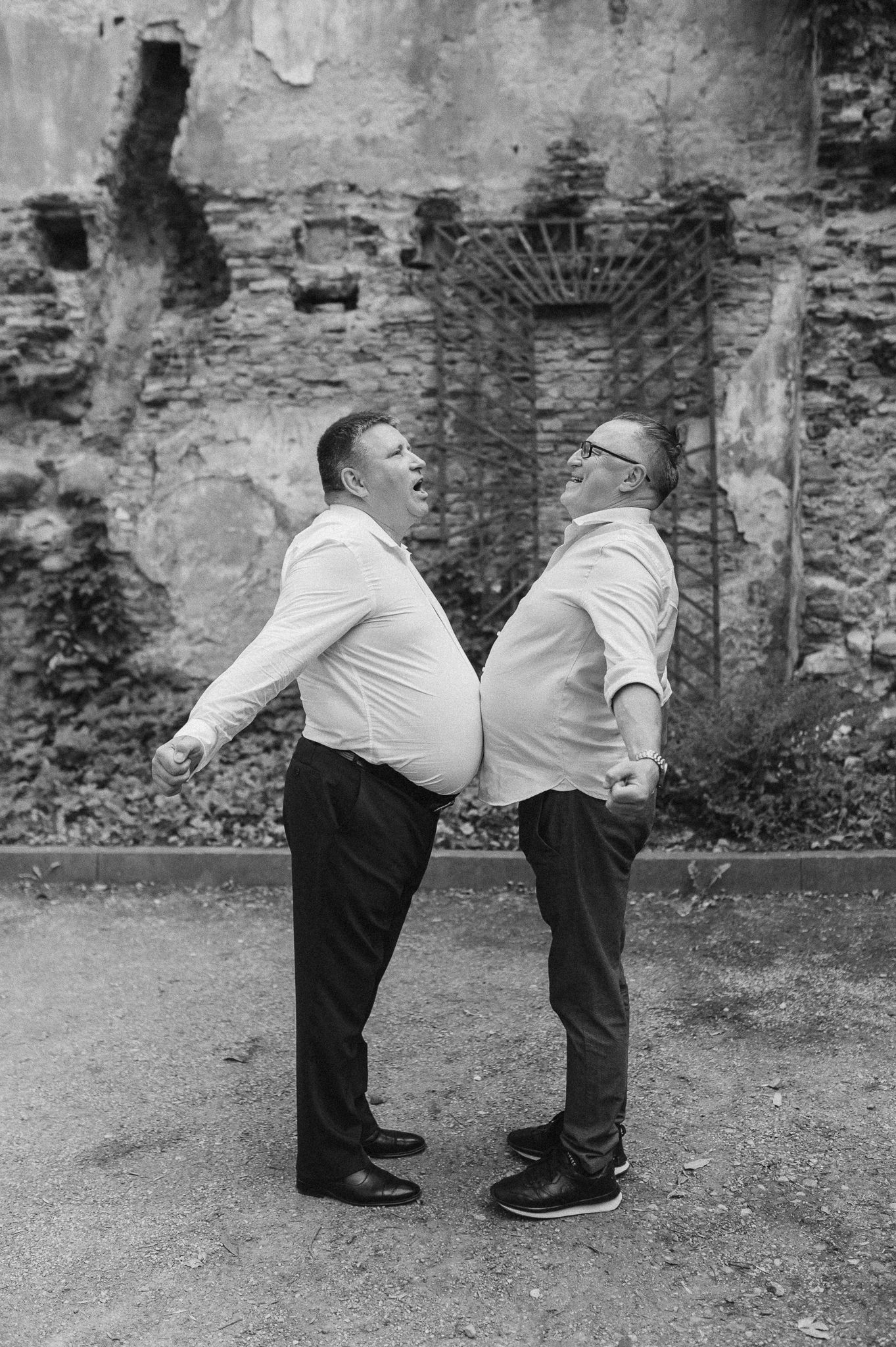 Two people in matching outfits playfully bending over in a humorous pose.