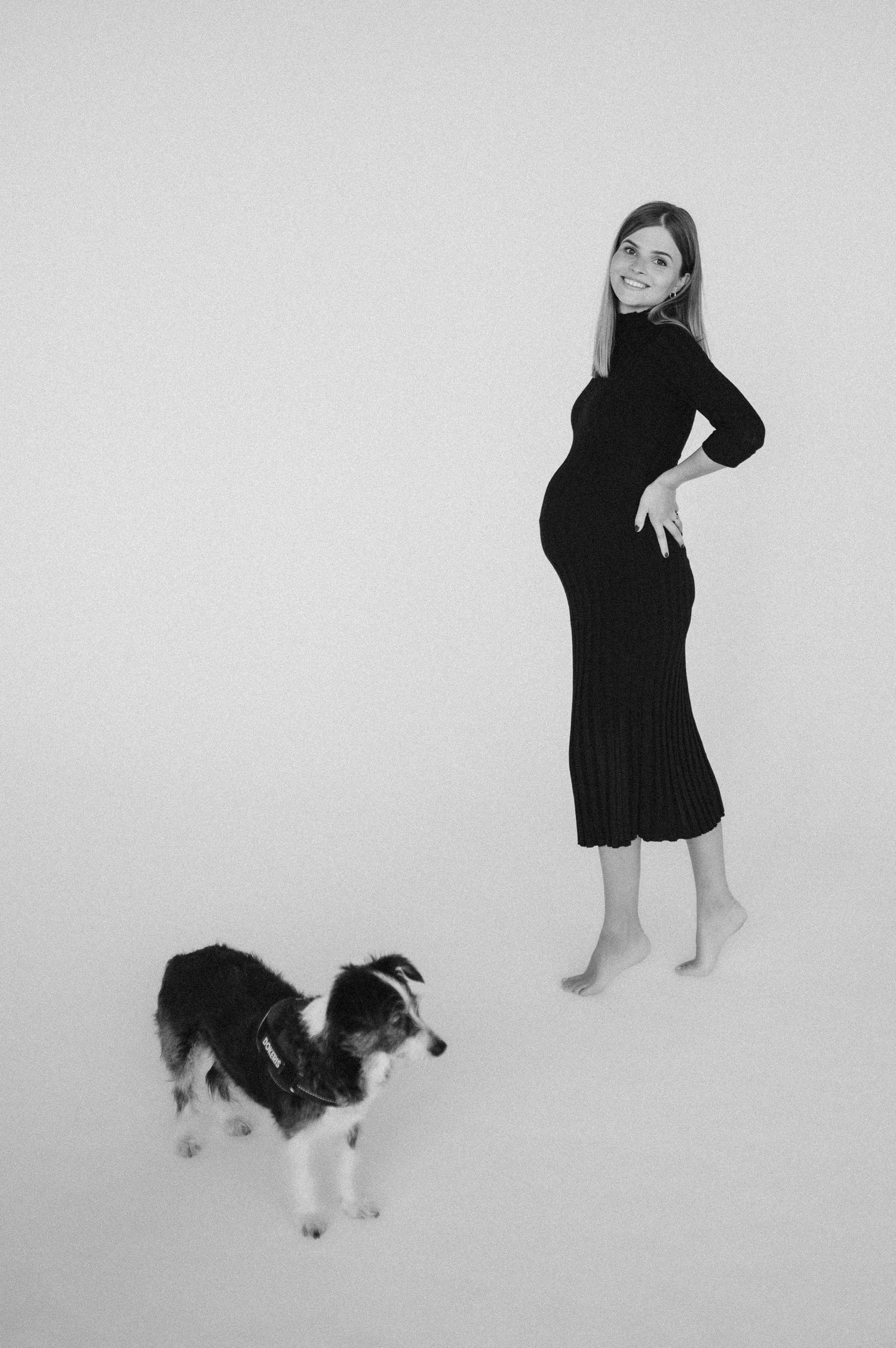 Black and white portraits with playful dog companion against minimalist background.