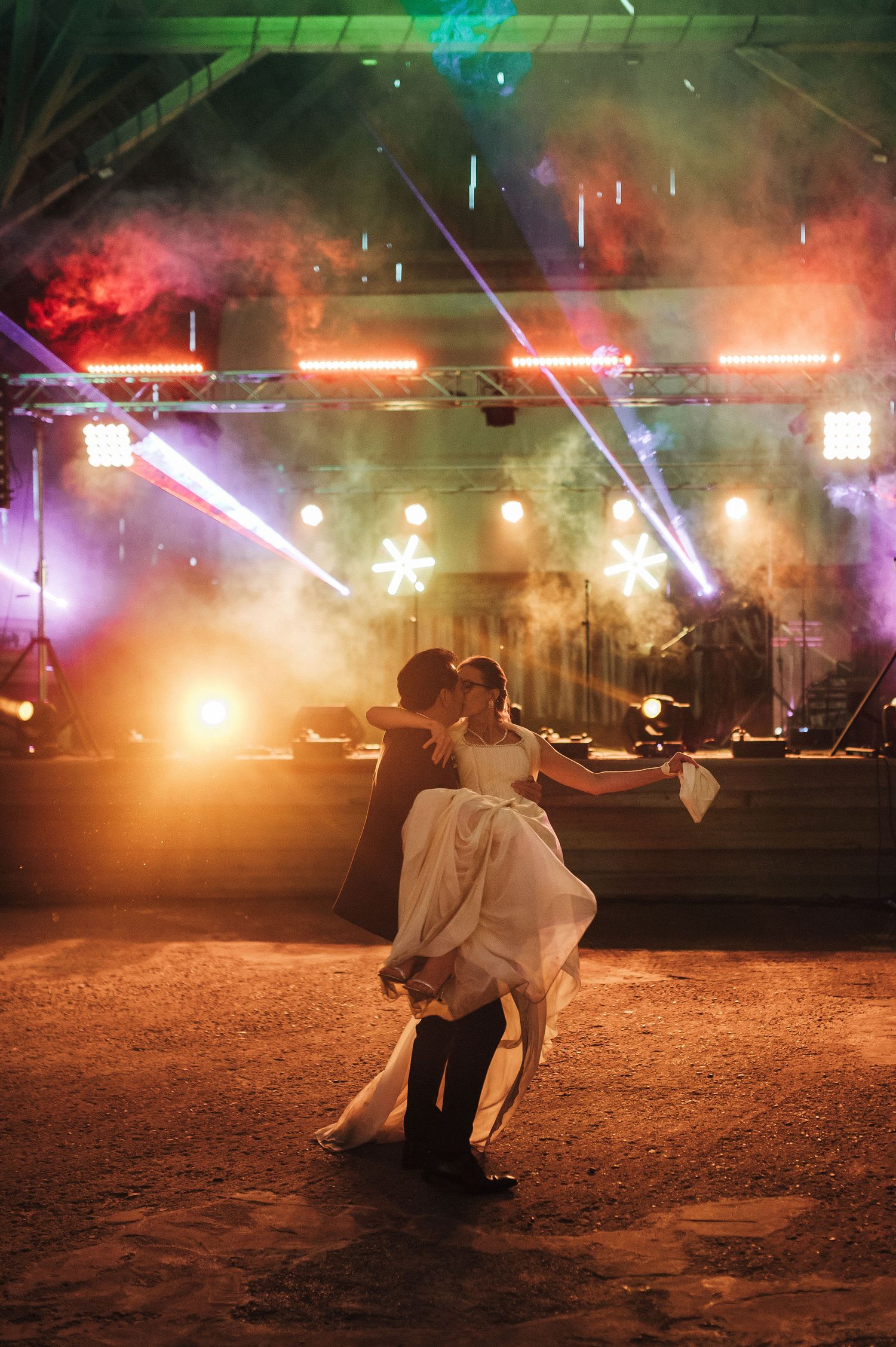 Dynamic nighttime wedding dance sequence with colorful stage lighting and smoke effects.
