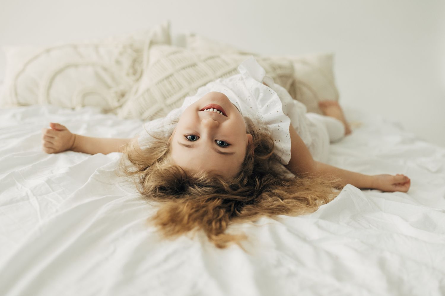 Series of relaxed poses on white bedding showing joyful, carefree moments.