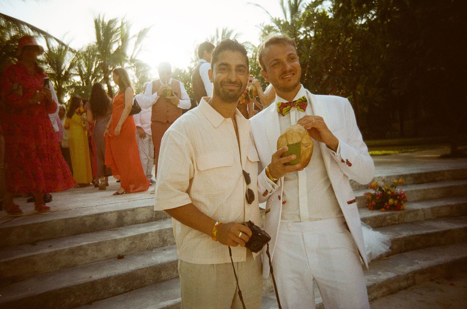 Wedding couple celebrates with palm trees and sunset backdrop during beach ceremony.
