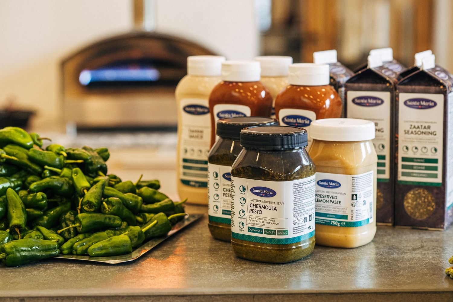 Various glass jars of supplements and vitamins arranged on a wooden surface next to fresh green vegetables.