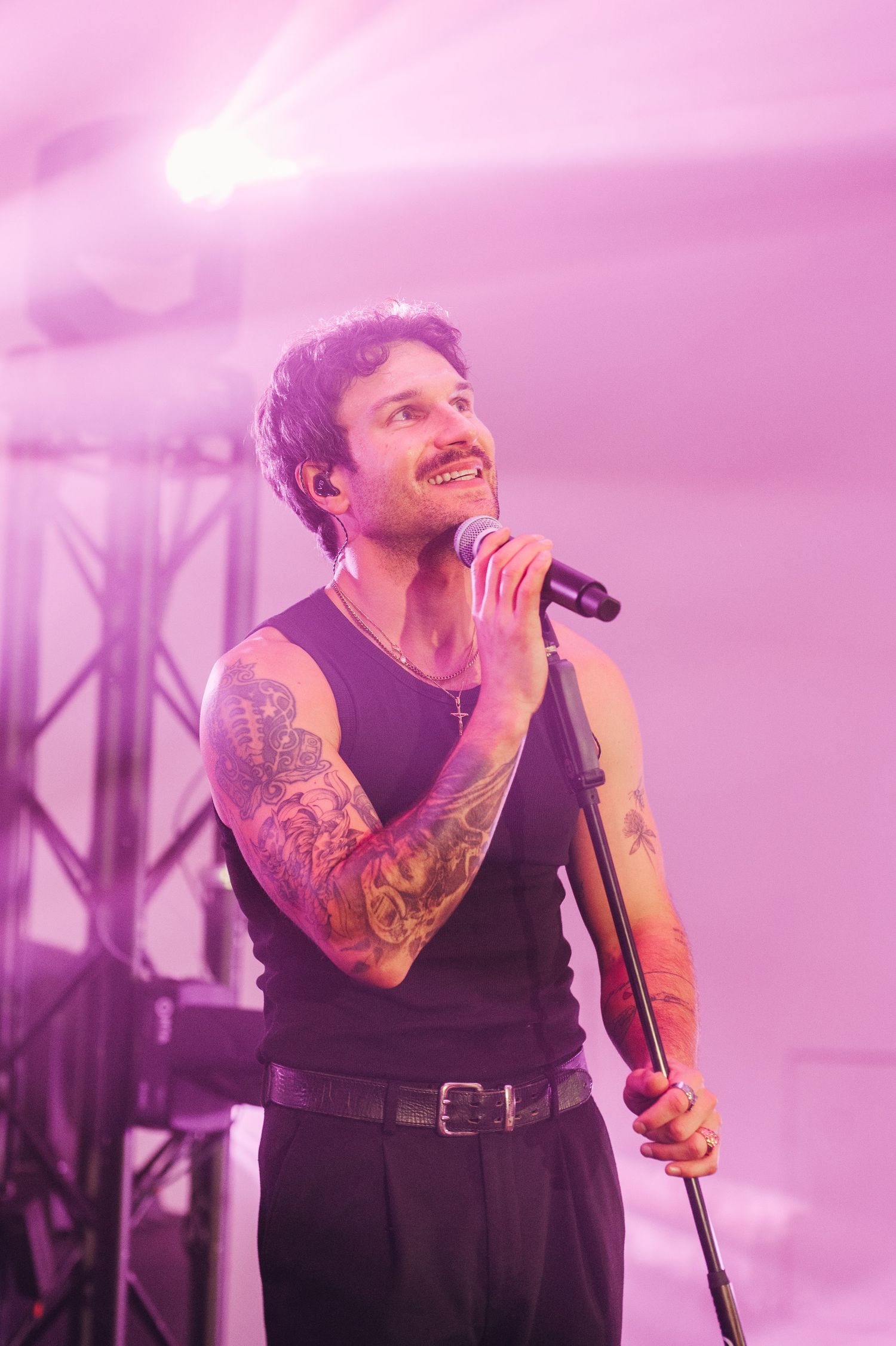 Concert performer singing passionately on stage bathed in pink lighting.