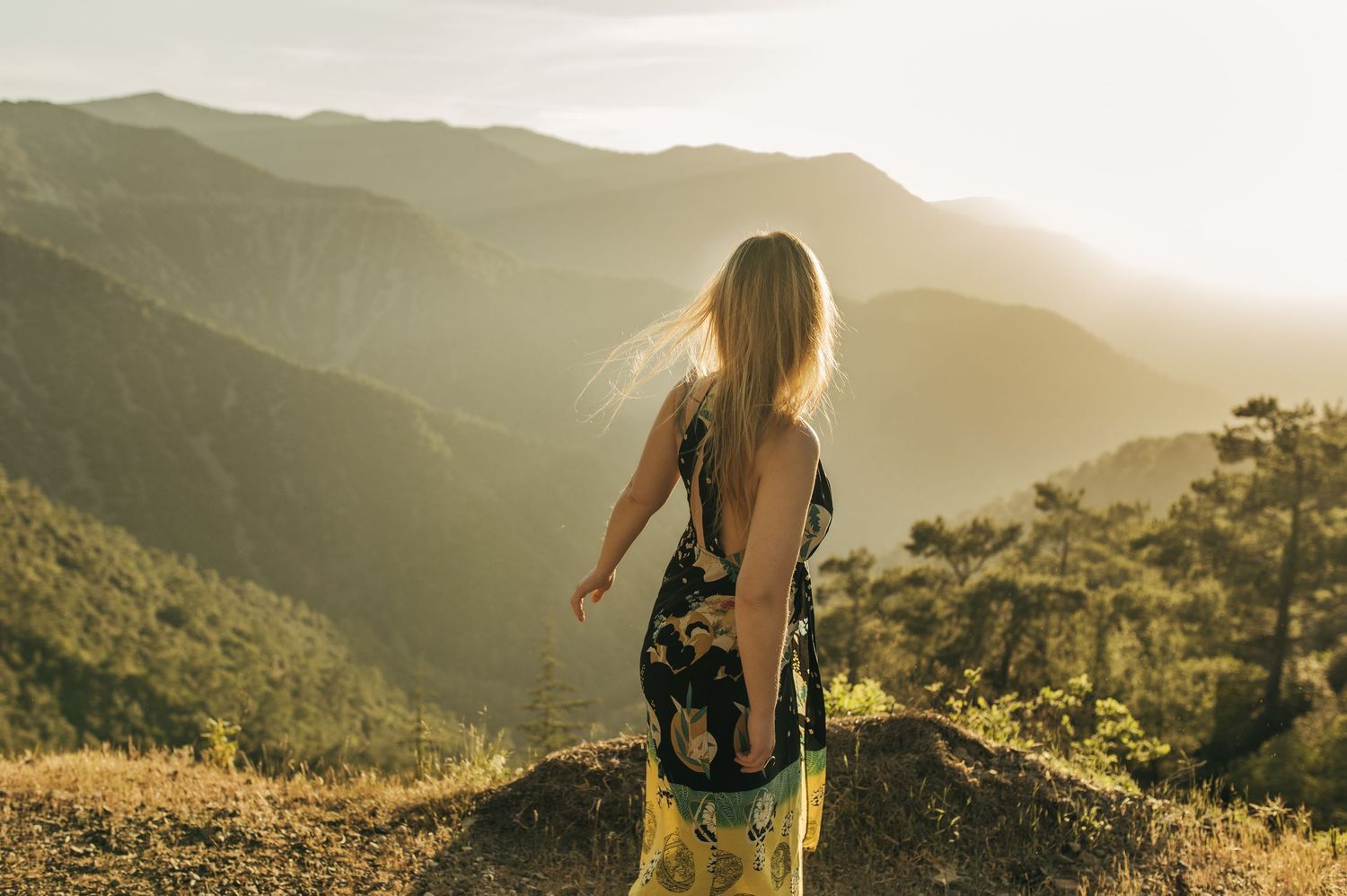 Silhouette of someone overlooking a majestic mountain landscape at golden hour.