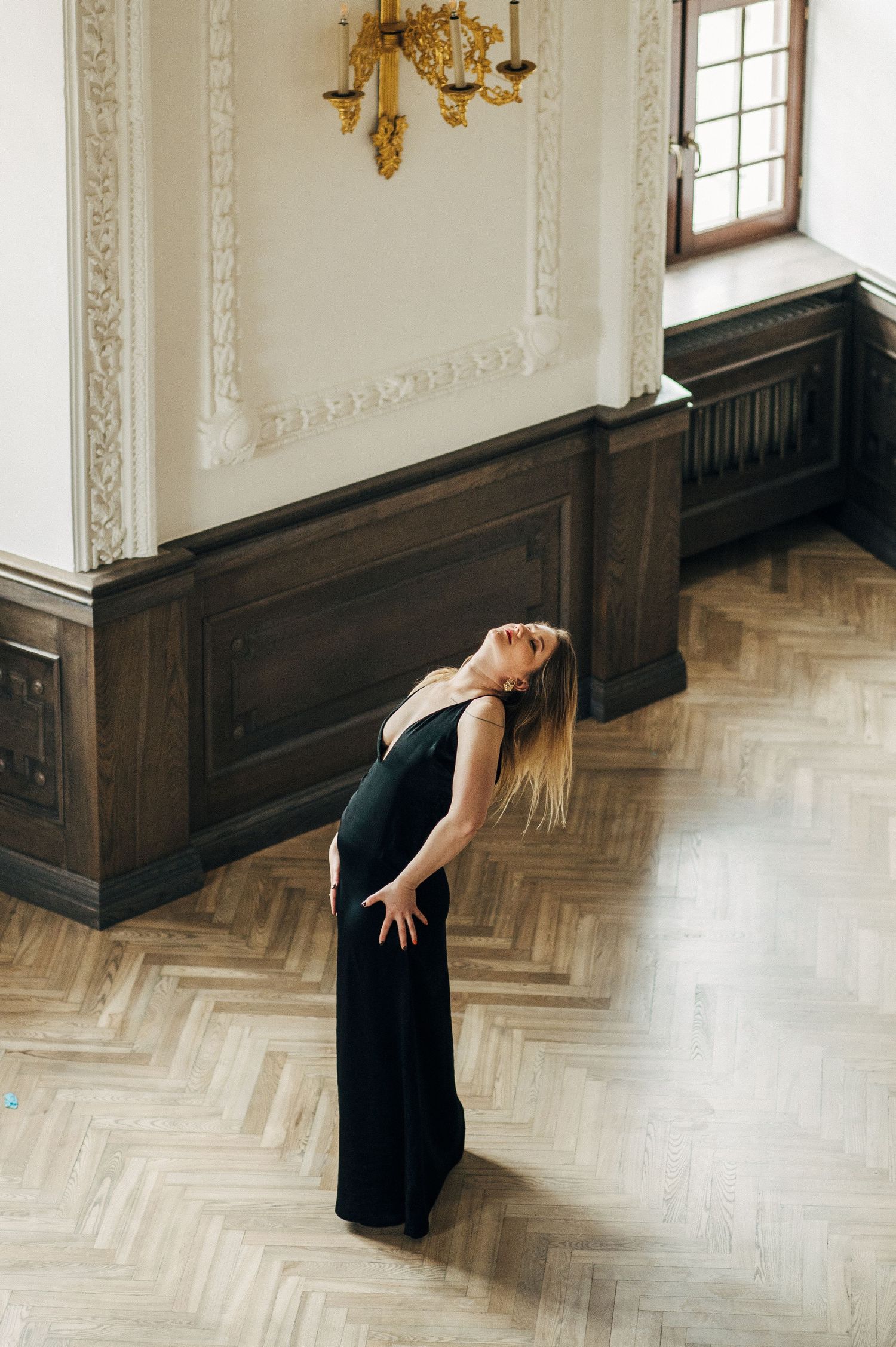 Elegant dance movements in black dress against ornate white and wood interior.
