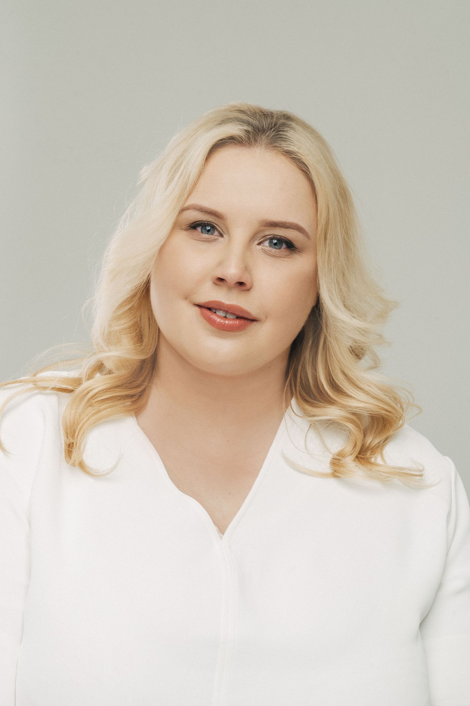 Professional headshots showing warm smile against light background wearing white top.