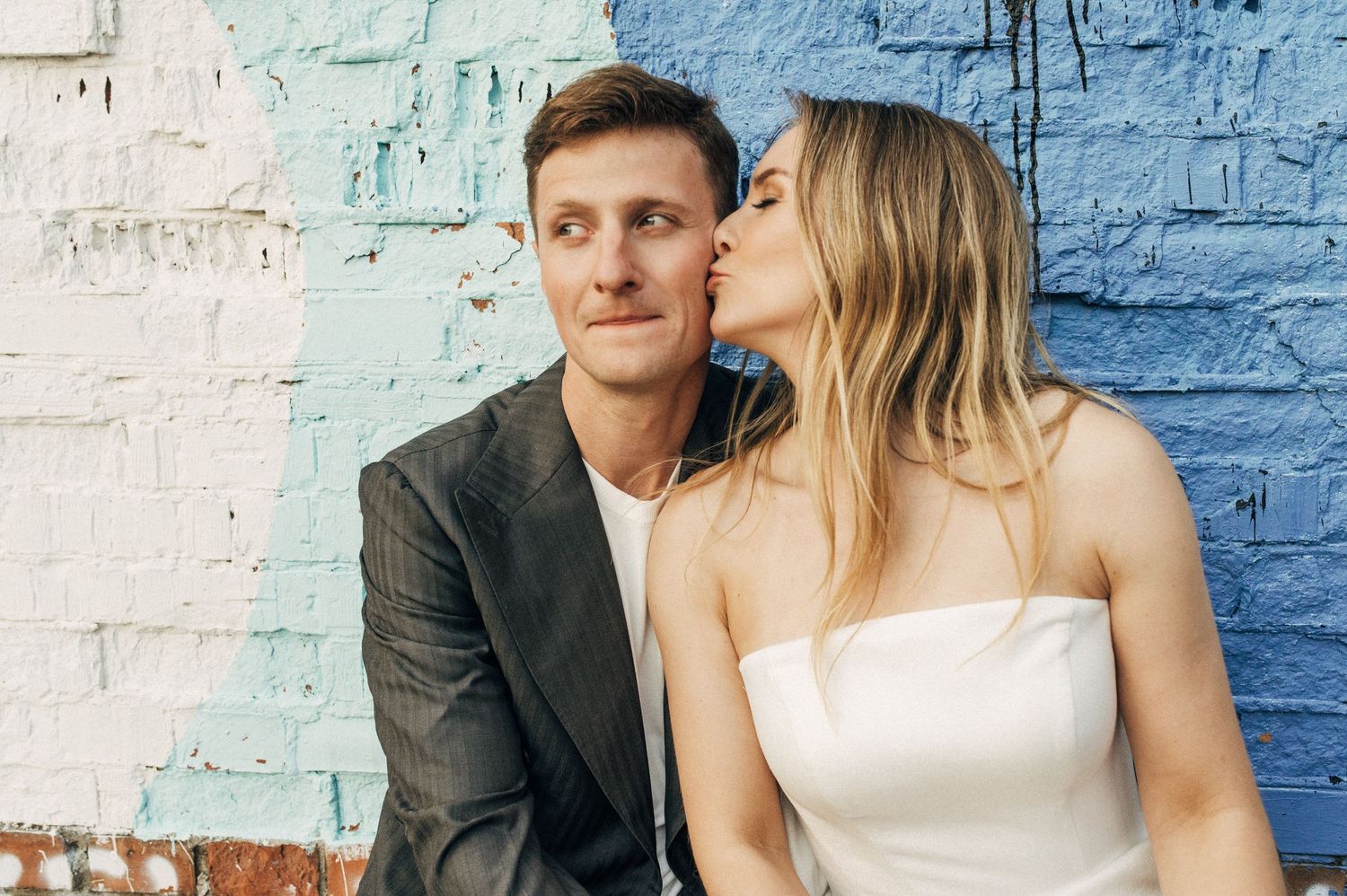 Romantic moment against colorful painted brick wall.