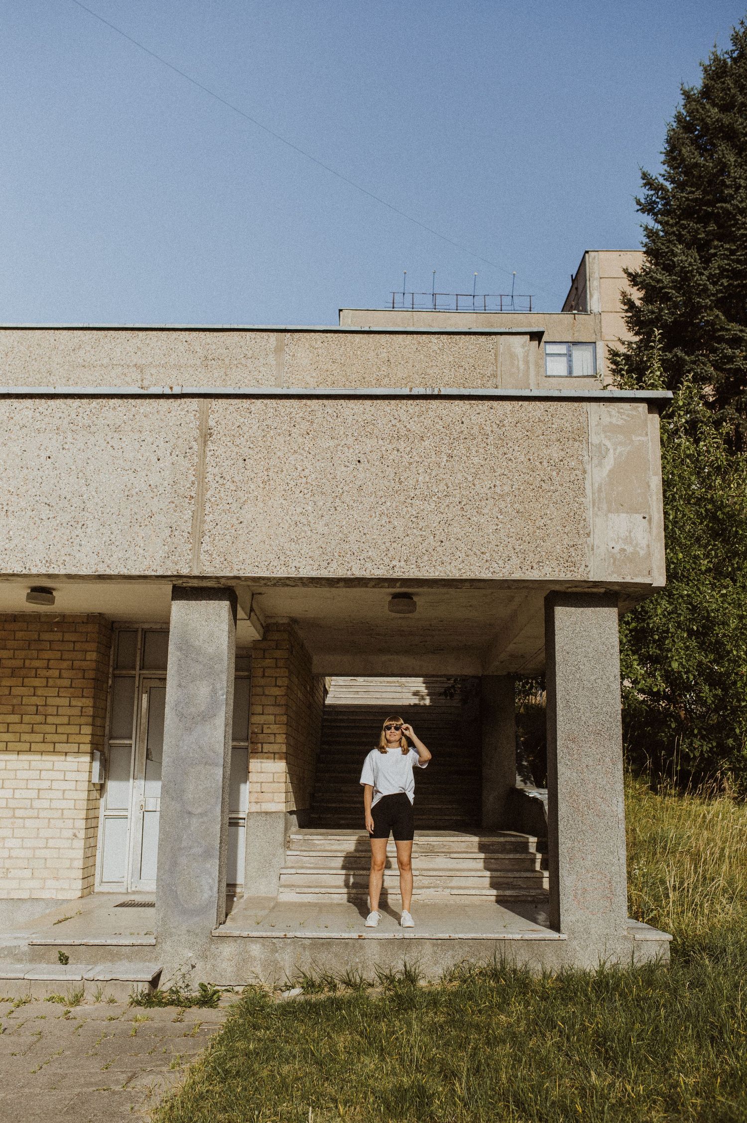 Series of shots showing figure moving across abandoned concrete building exterior.