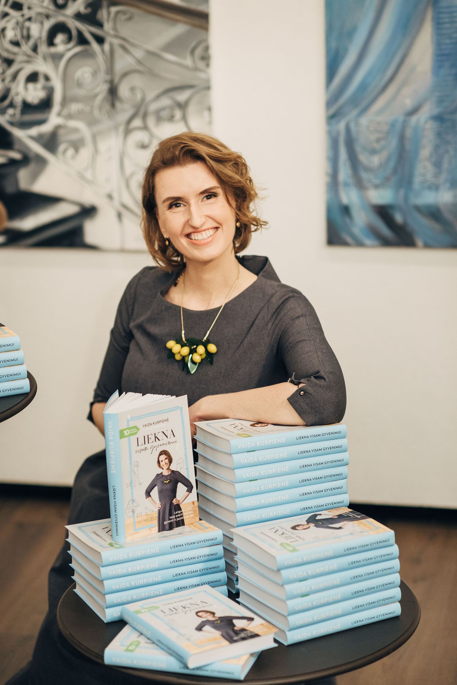 Book signing event setup with stacks of blue-covered books displayed on a round table.