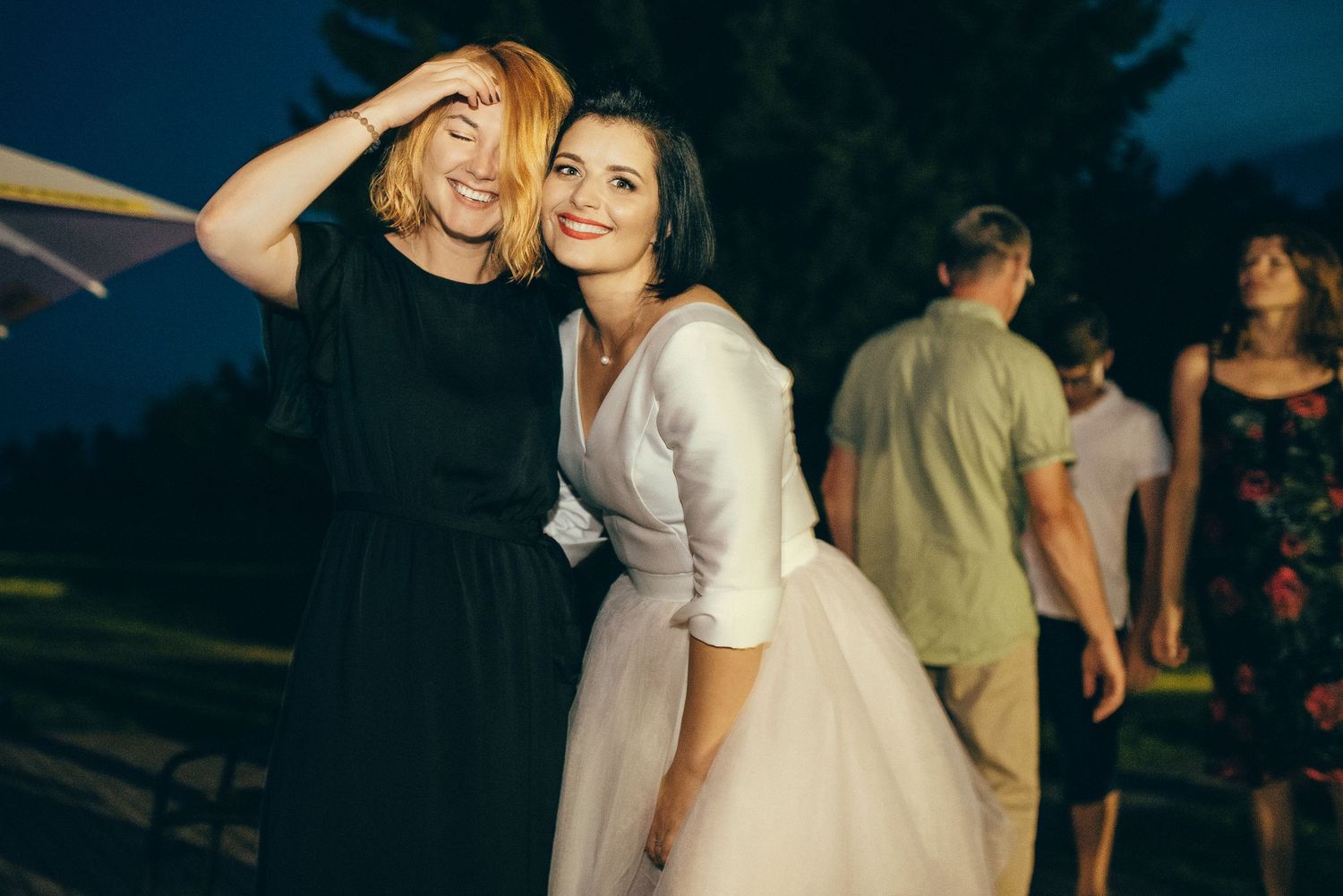 Wedding celebration at dusk with guests dancing outdoors.