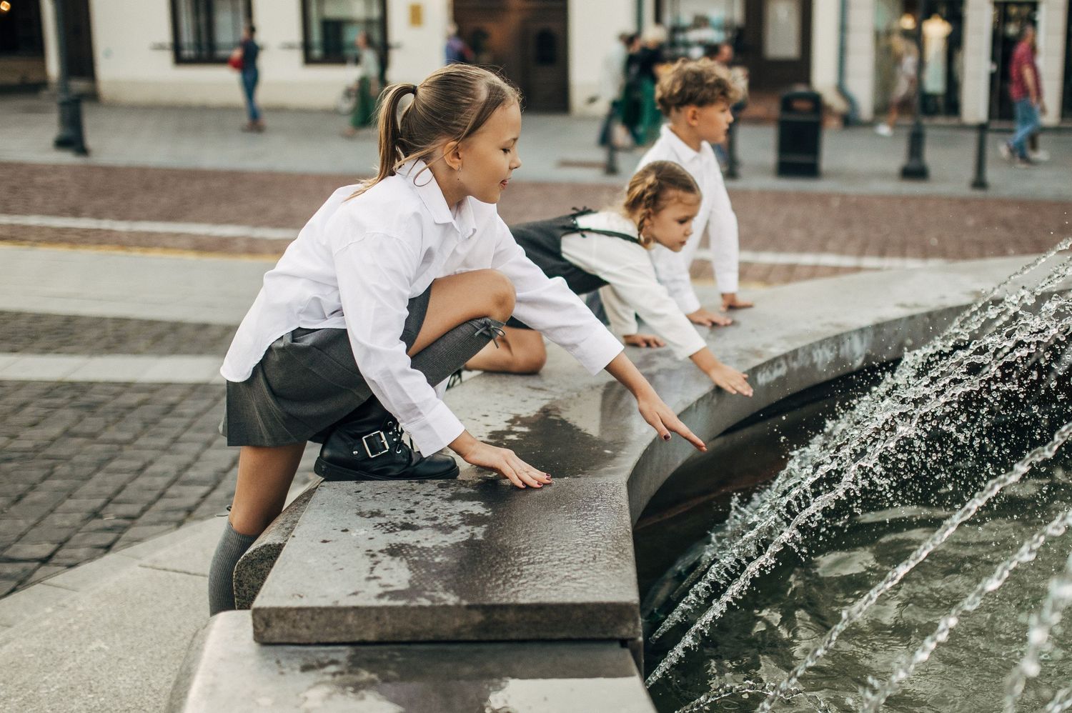 Children playing by a fountain in an urban square.
