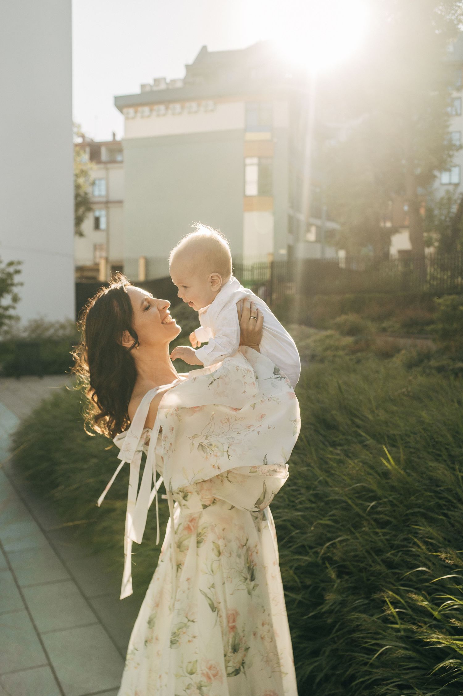 Sweet moment captured in golden sunlight with floral dress and natural backlight.