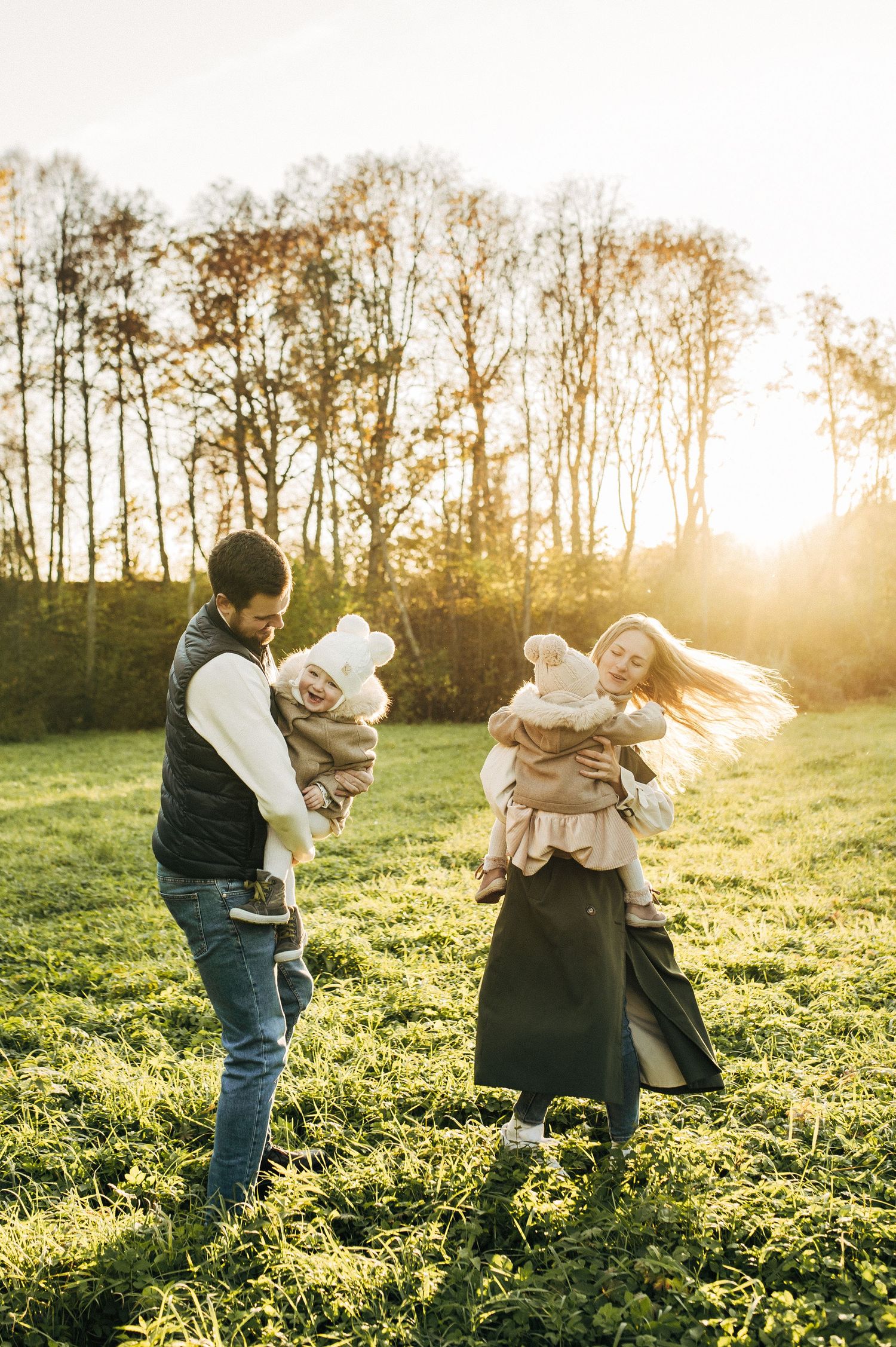 Family playing in a sunlit field during golden hour.