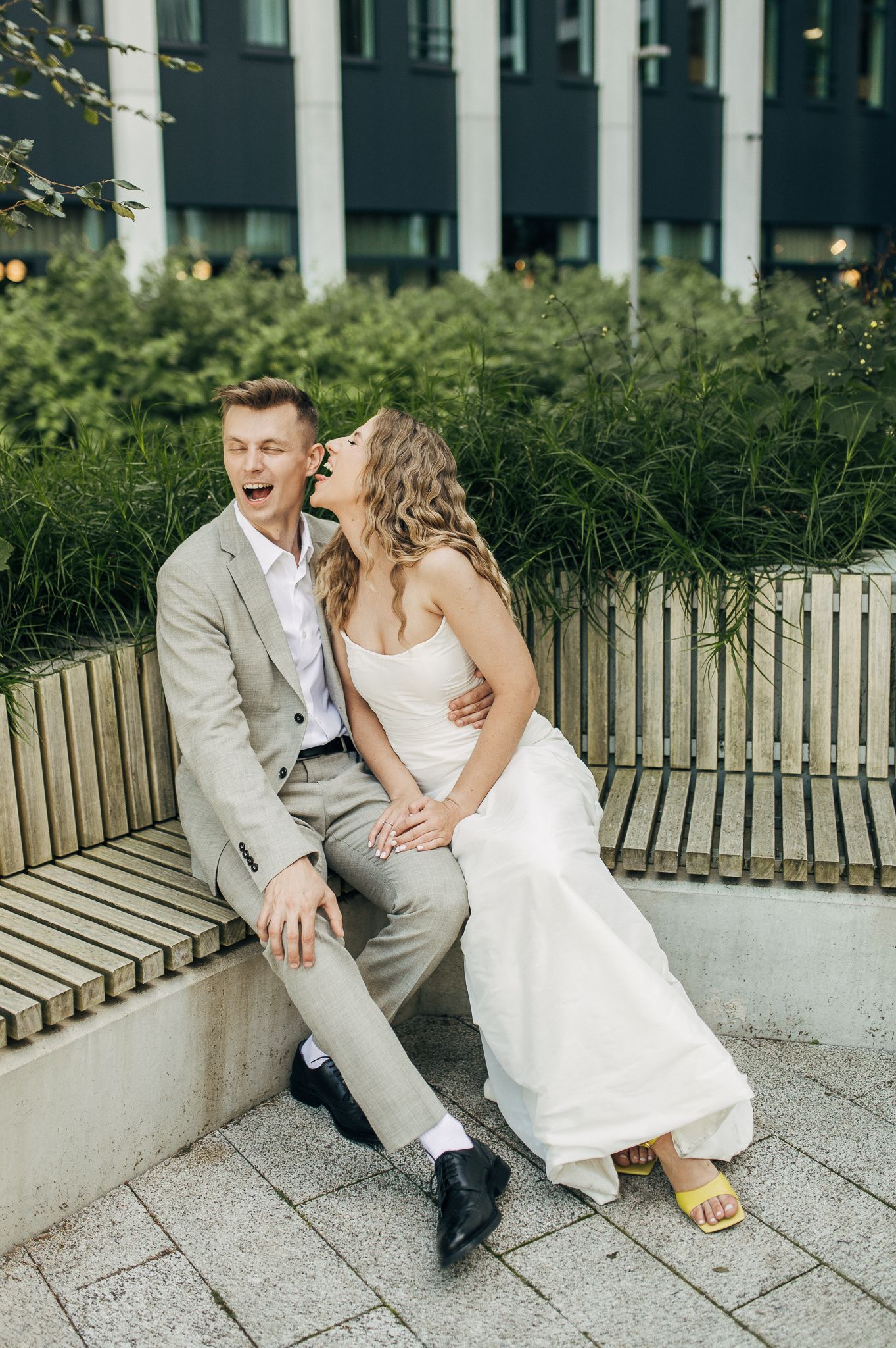 Romantic wedding couple sitting and interacting on outdoor steps in elegant attire.