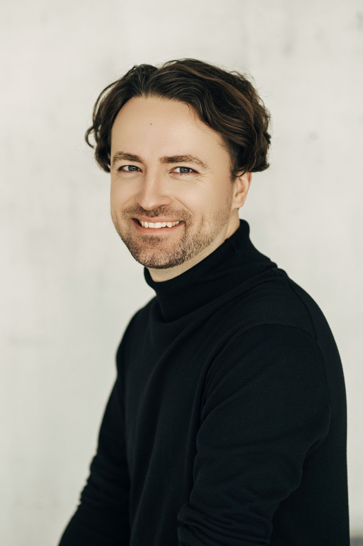 Portrait series of someone in black turtleneck showing candid expressions against white background.