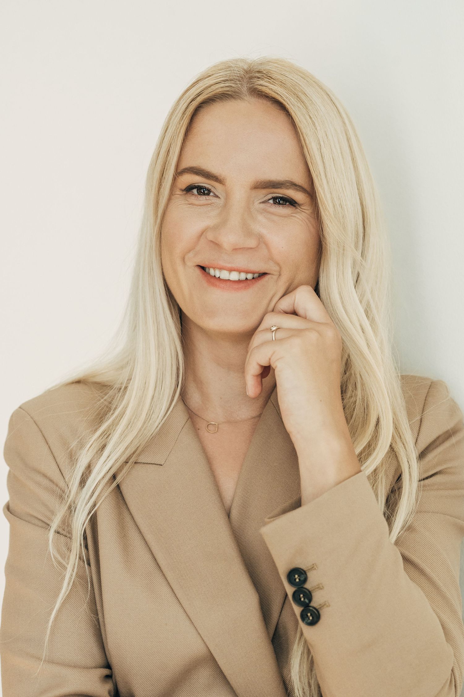 Fashion portrait series in beige blazer showing candid expressions against white background.