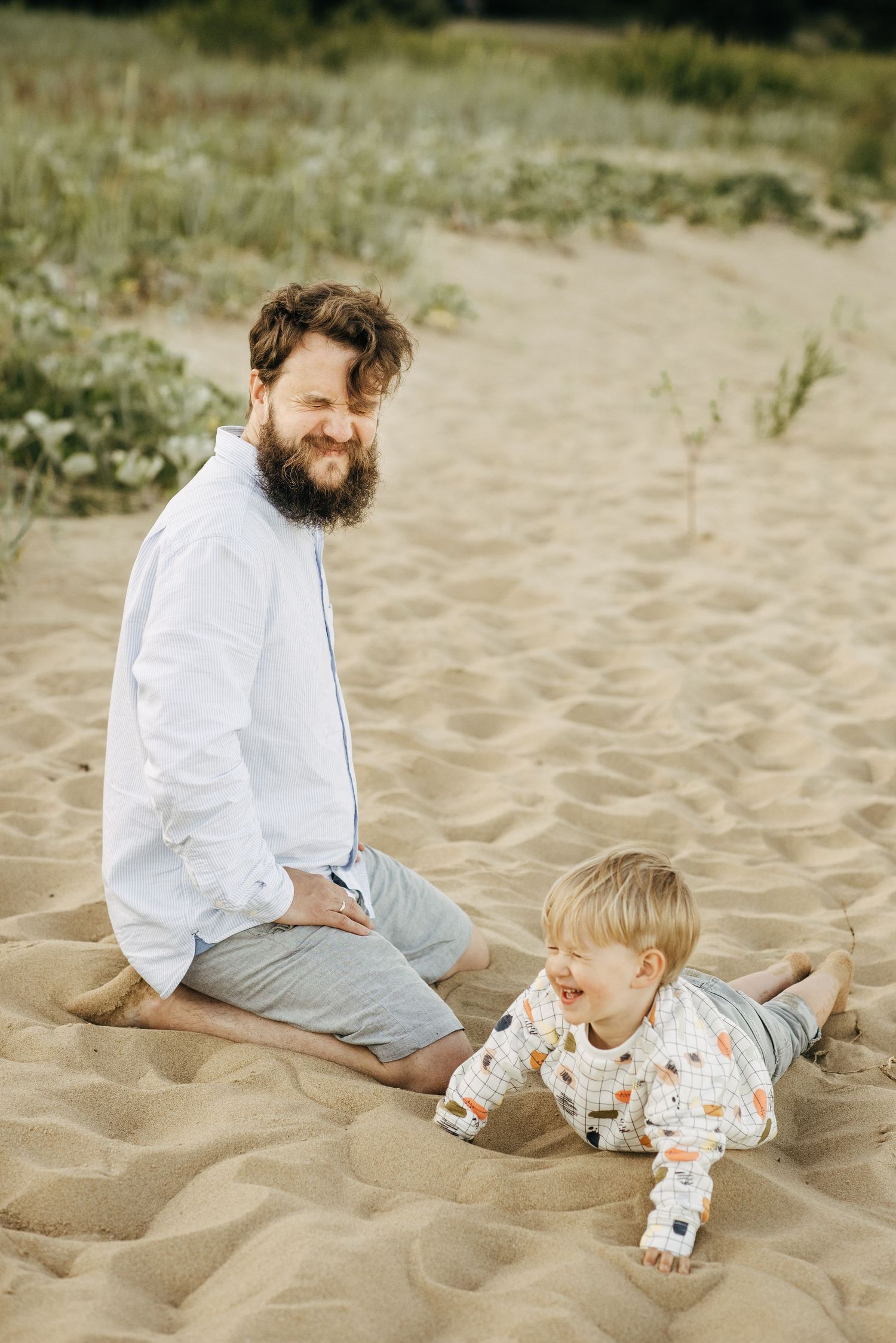 Two people sitting together on sandy beach enjoying a peaceful moment.