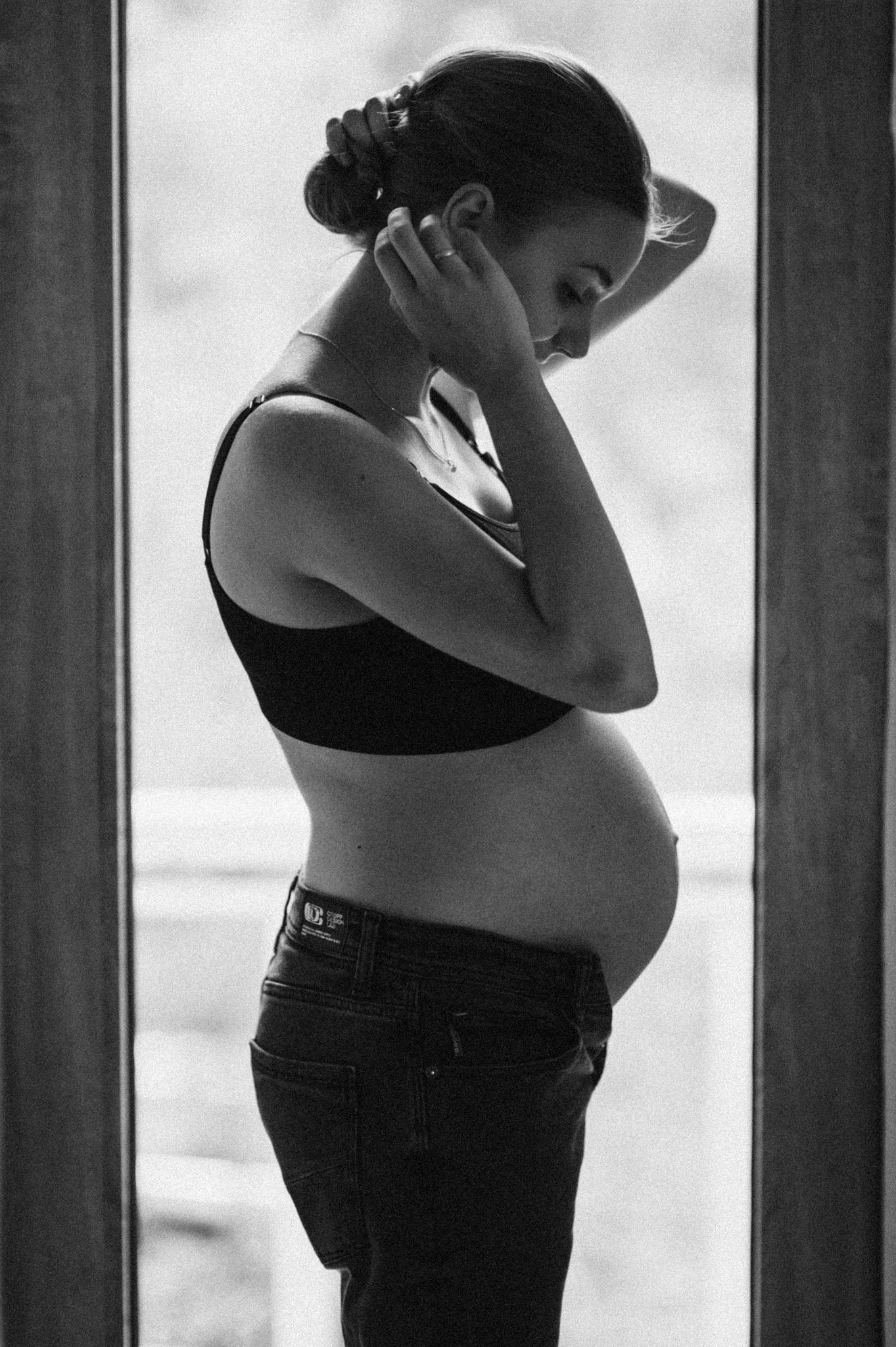 Artistic silhouette photos showing a pregnant figure in black and white against natural light.