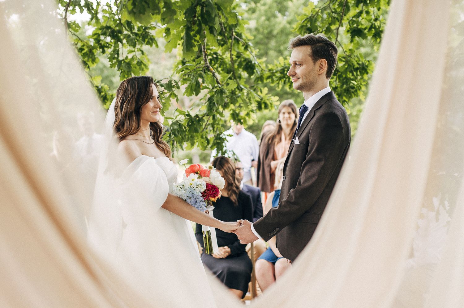 Intimate wedding ceremony moment under green vine archway.