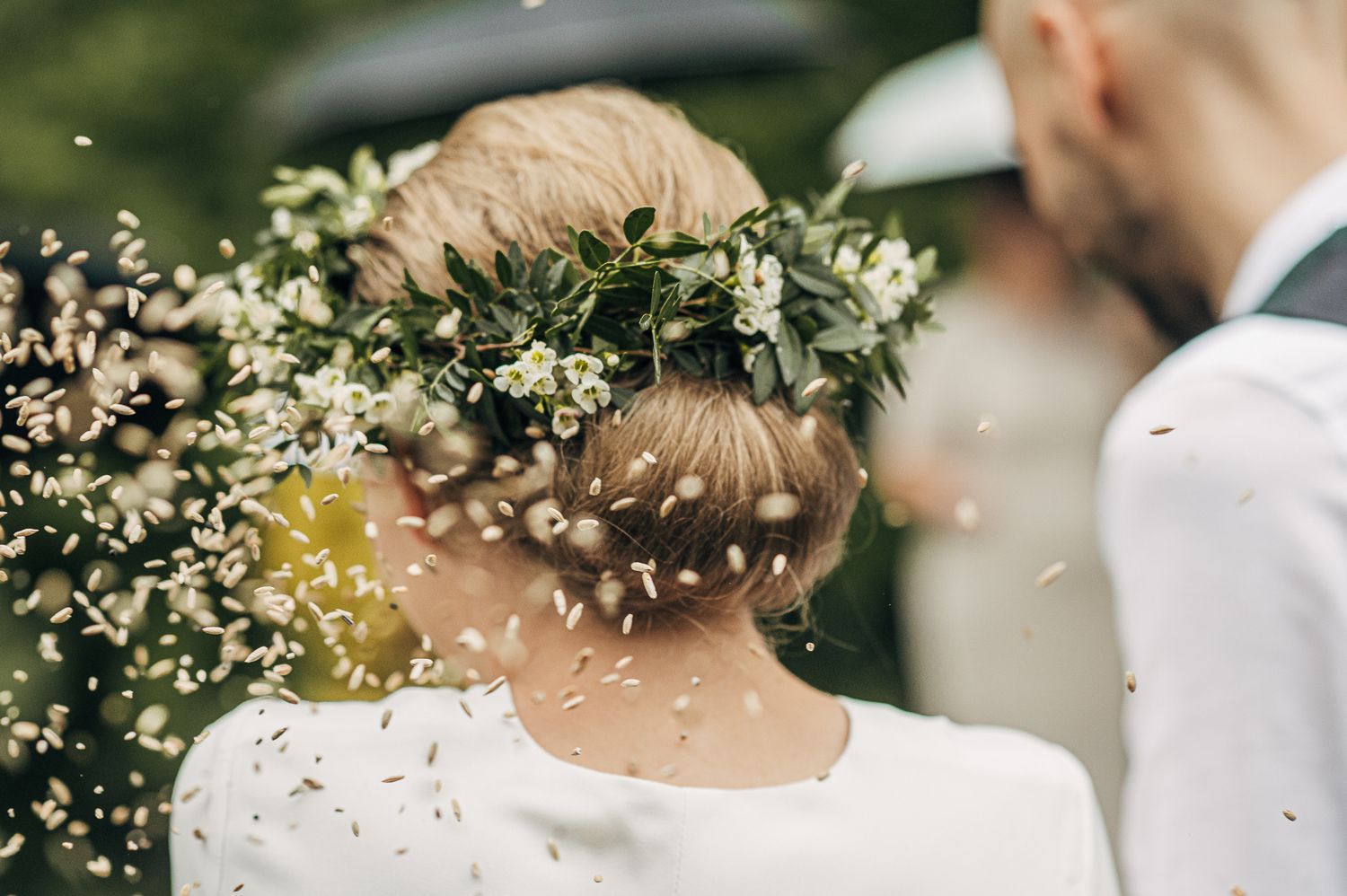 White flower crown adorns head at an outdoor wedding celebration.