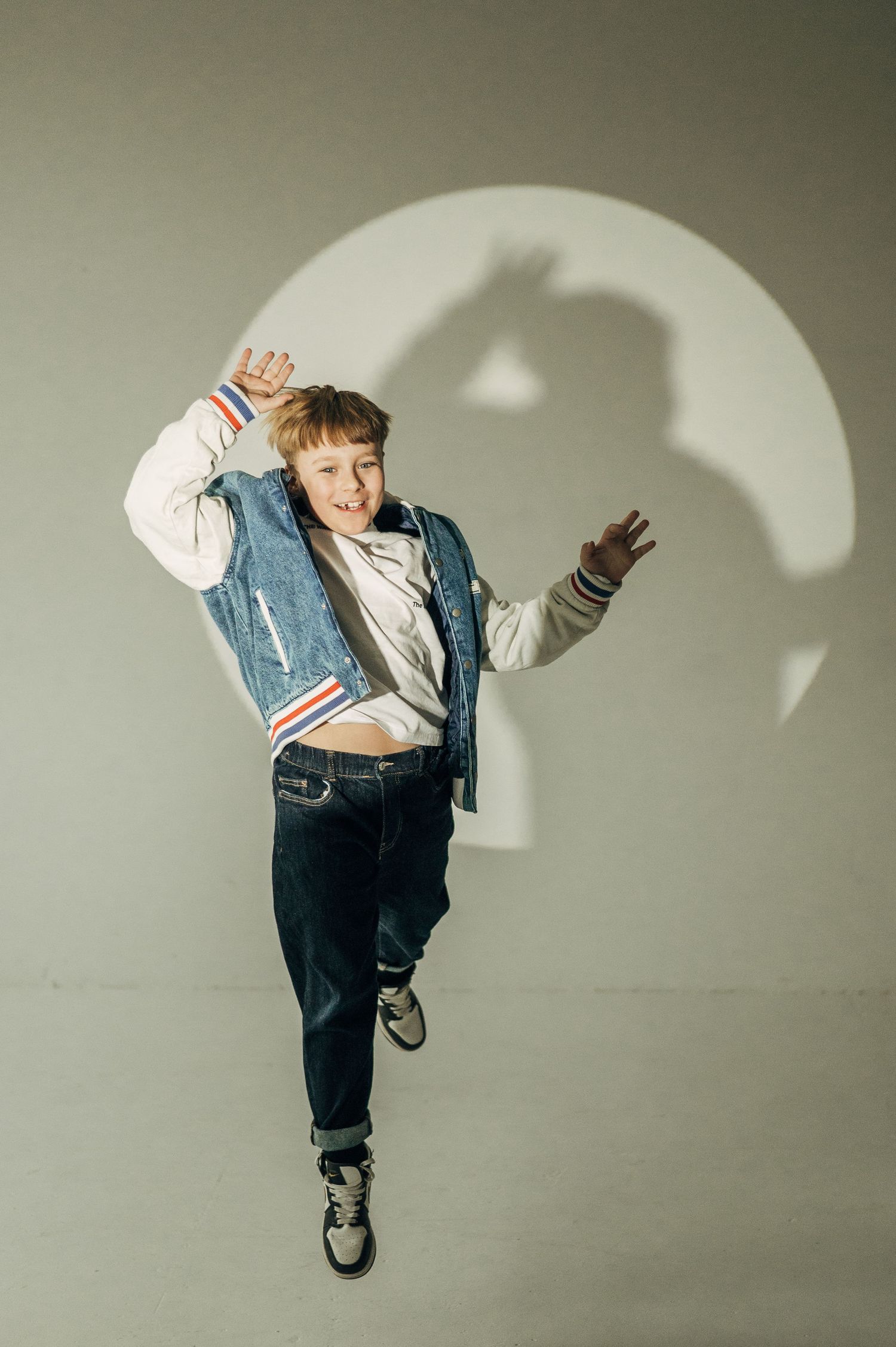 A series of dynamic dance poses by a young child wearing denim and a jean jacket.
